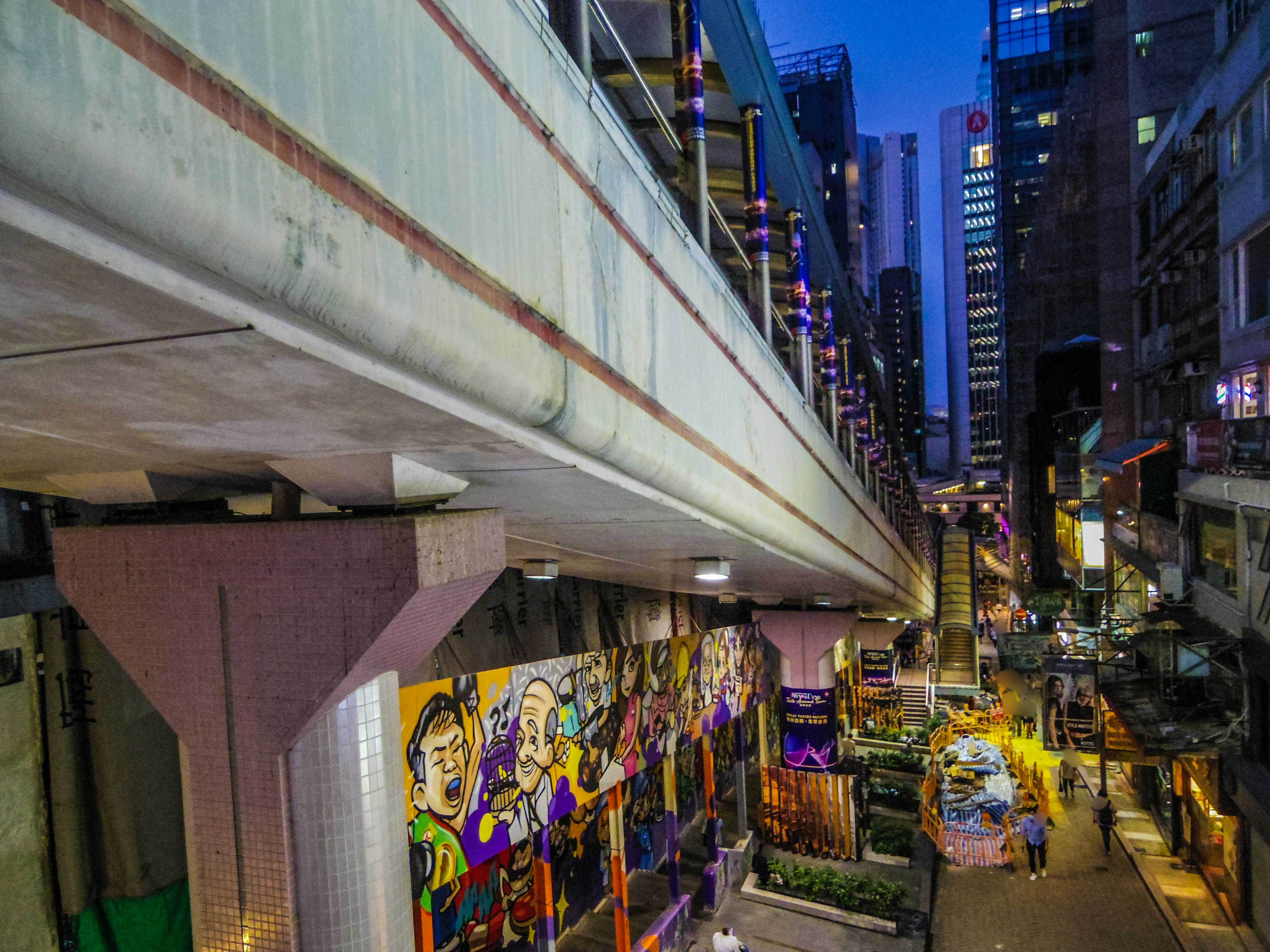 Vista nocturna de una ciudad con rascacielos y graffiti colorido bajo un paso elevado