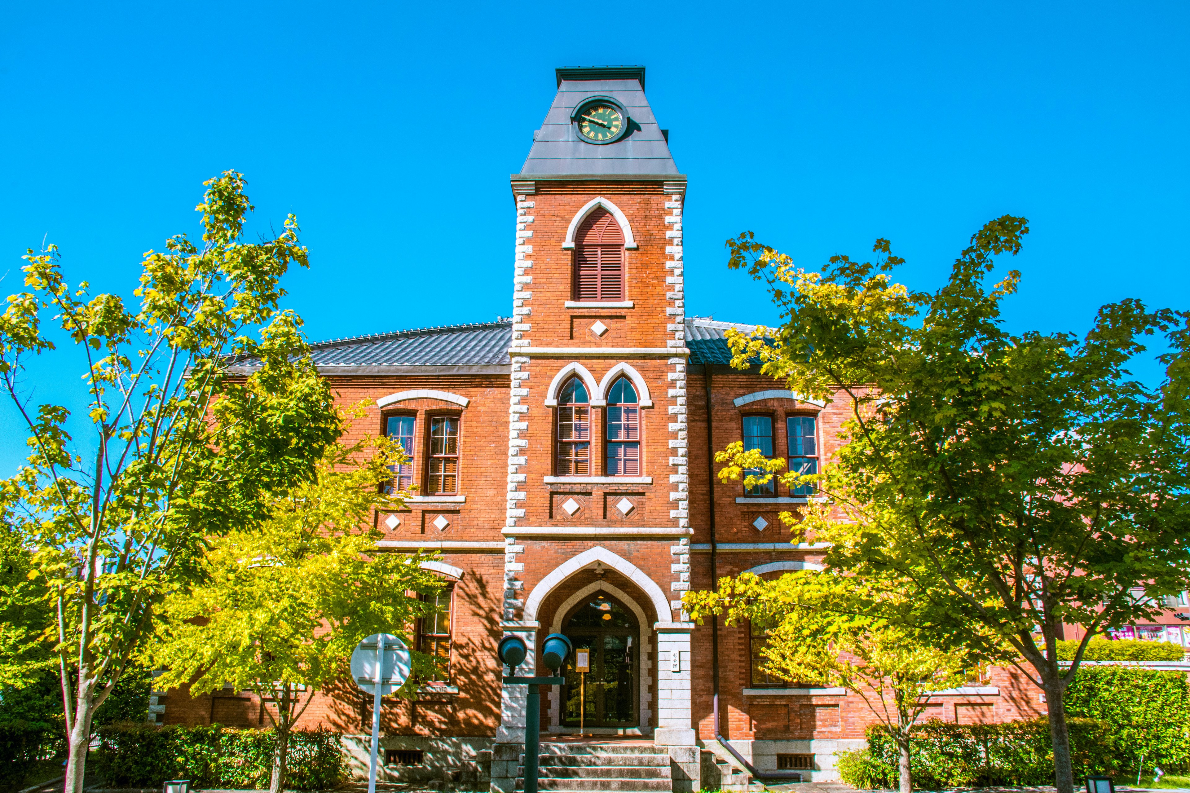 Historic red brick building with green trees and clear blue sky