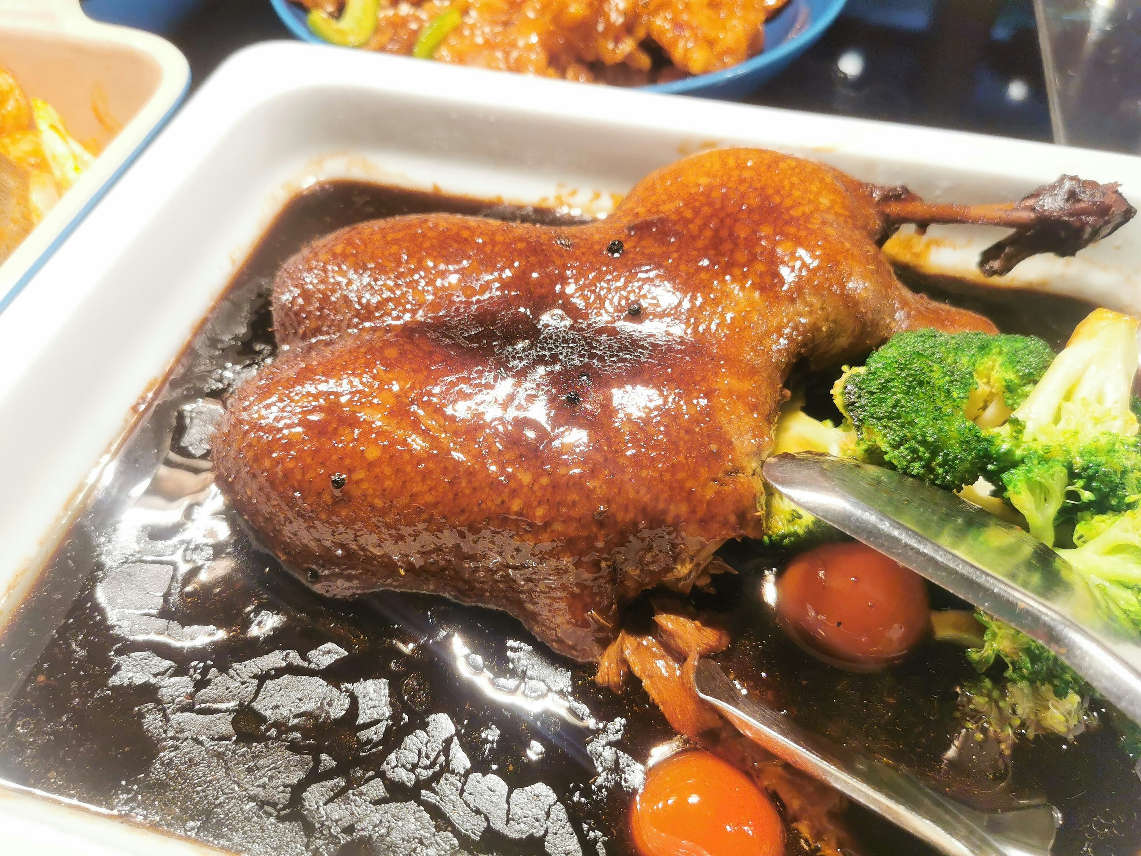 Plato de pato glaseado con brócoli y tomates cherry