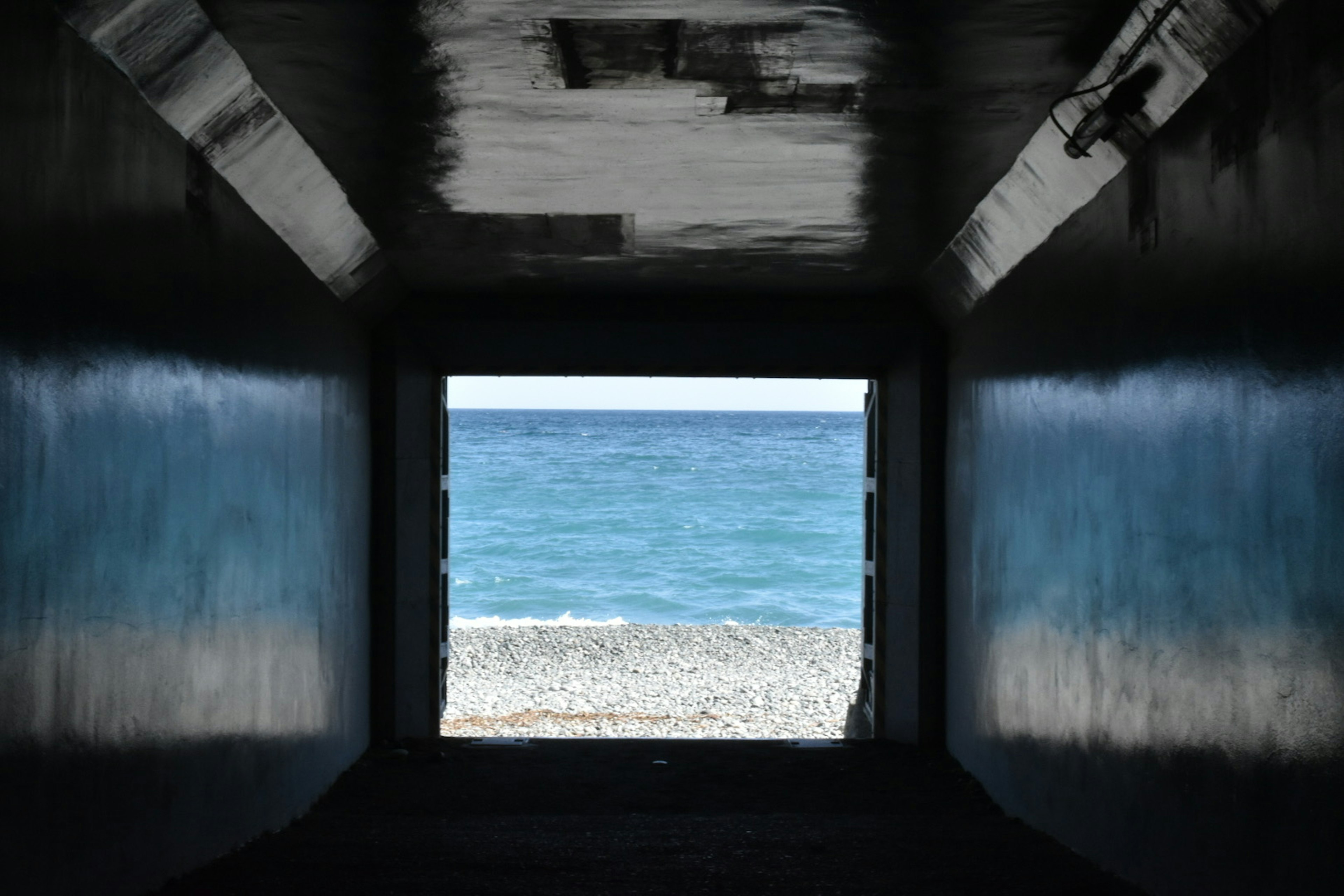 Blick auf das blaue Meer und den Sandstrand durch einen Tunnel