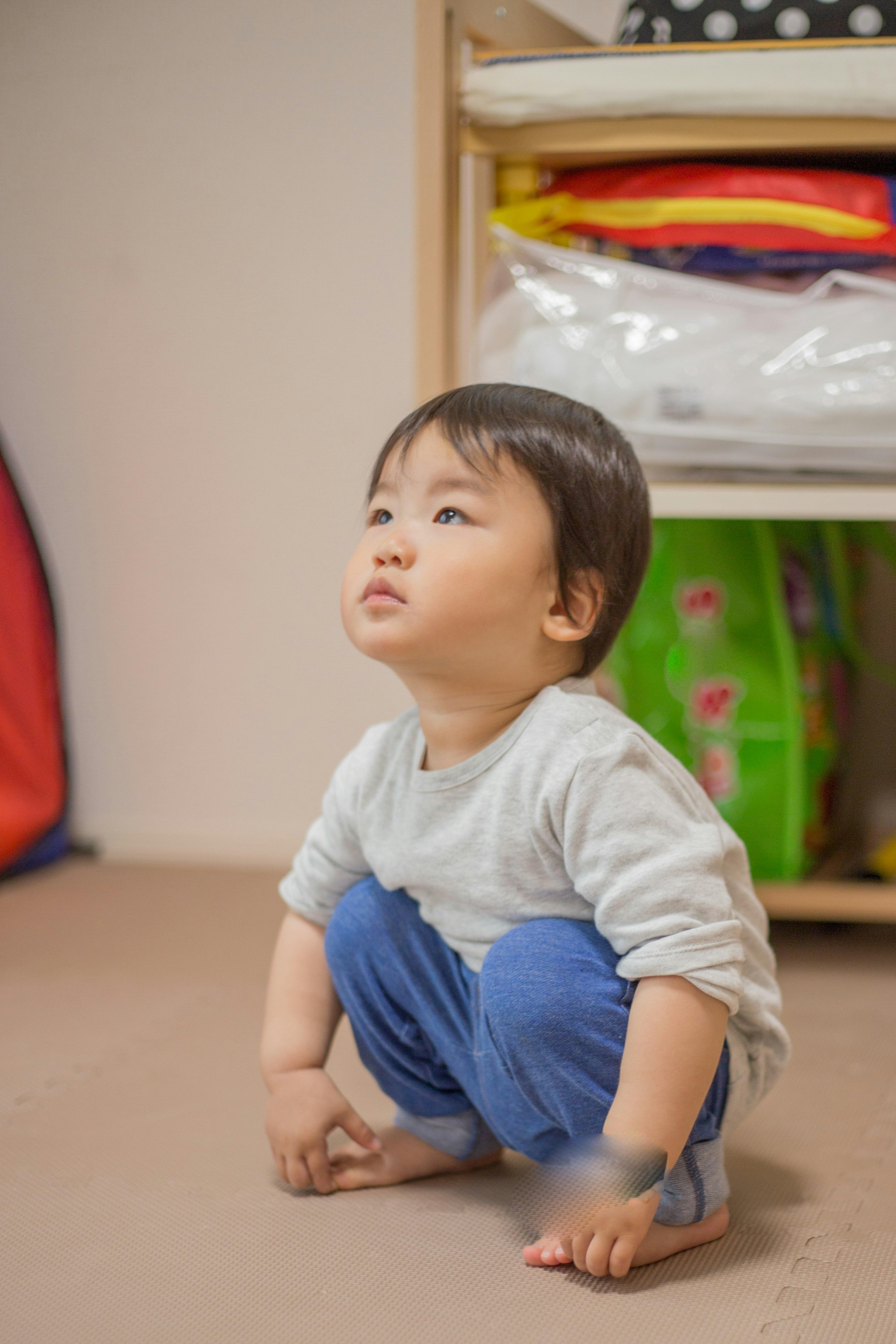 Un bambino accovacciato che guarda in alto con interesse