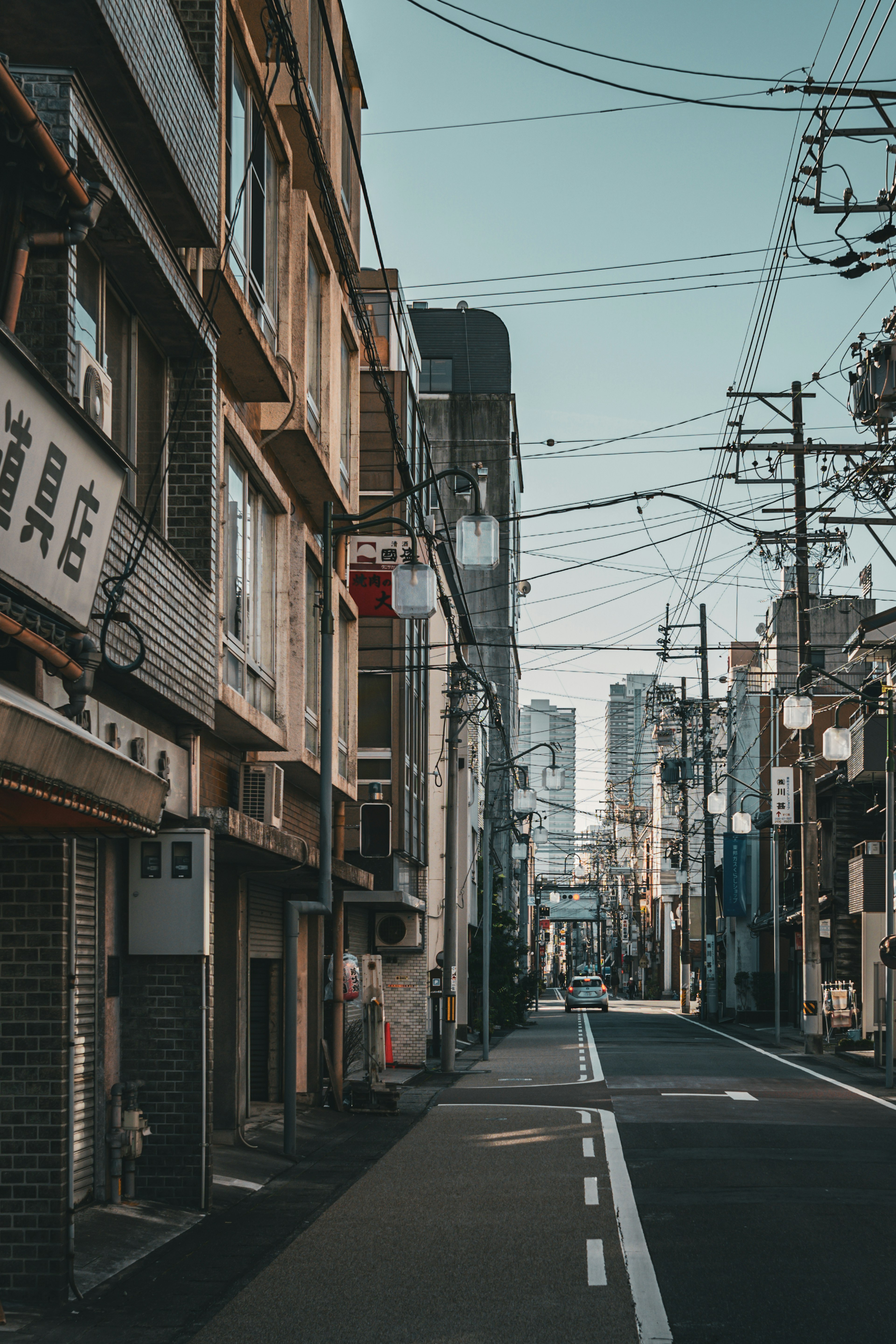 狭い街路に沿ったビルと電線が見える風景