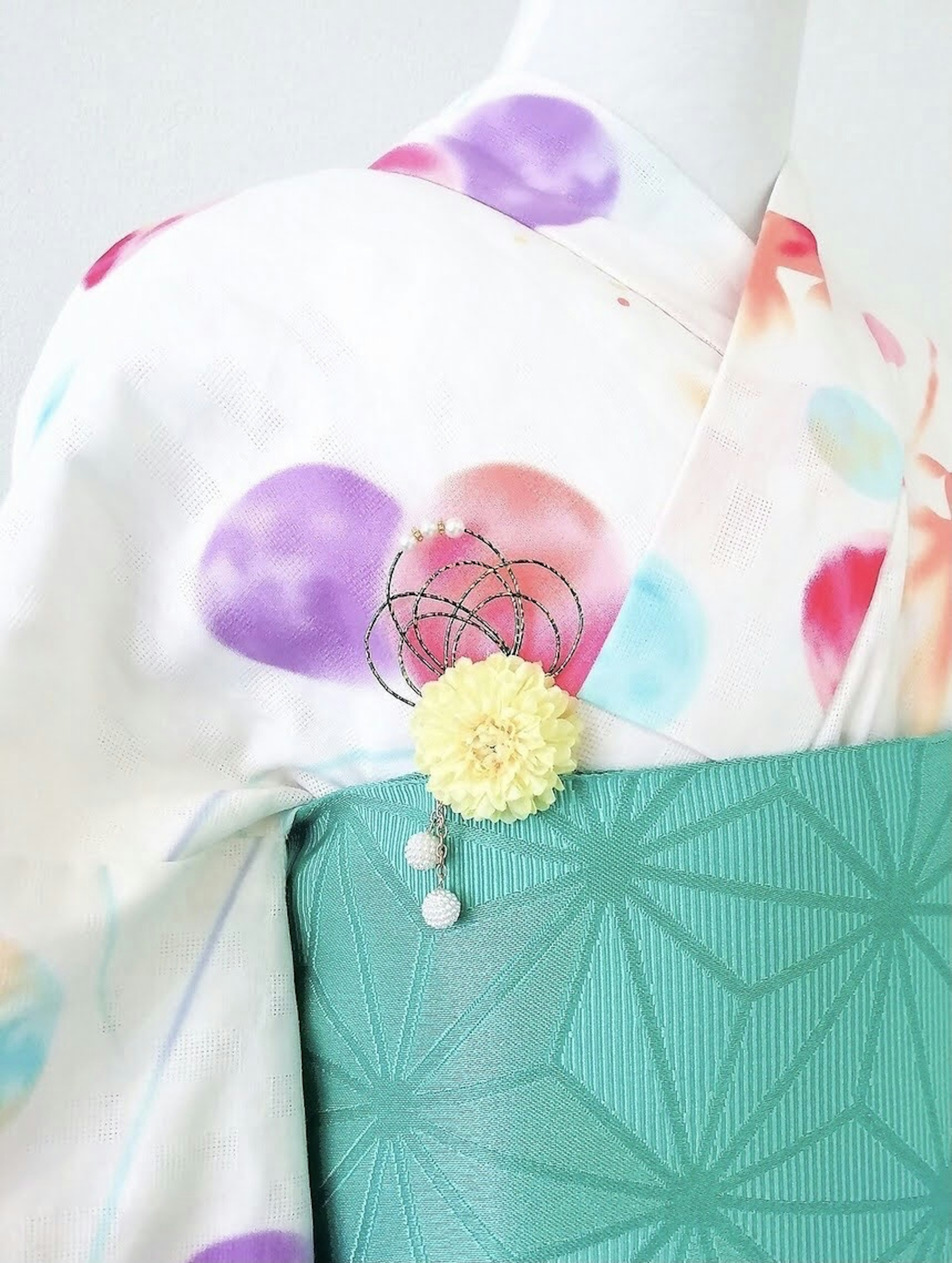 Kimono with colorful polka dots on white background and a green obi featuring geometric patterns