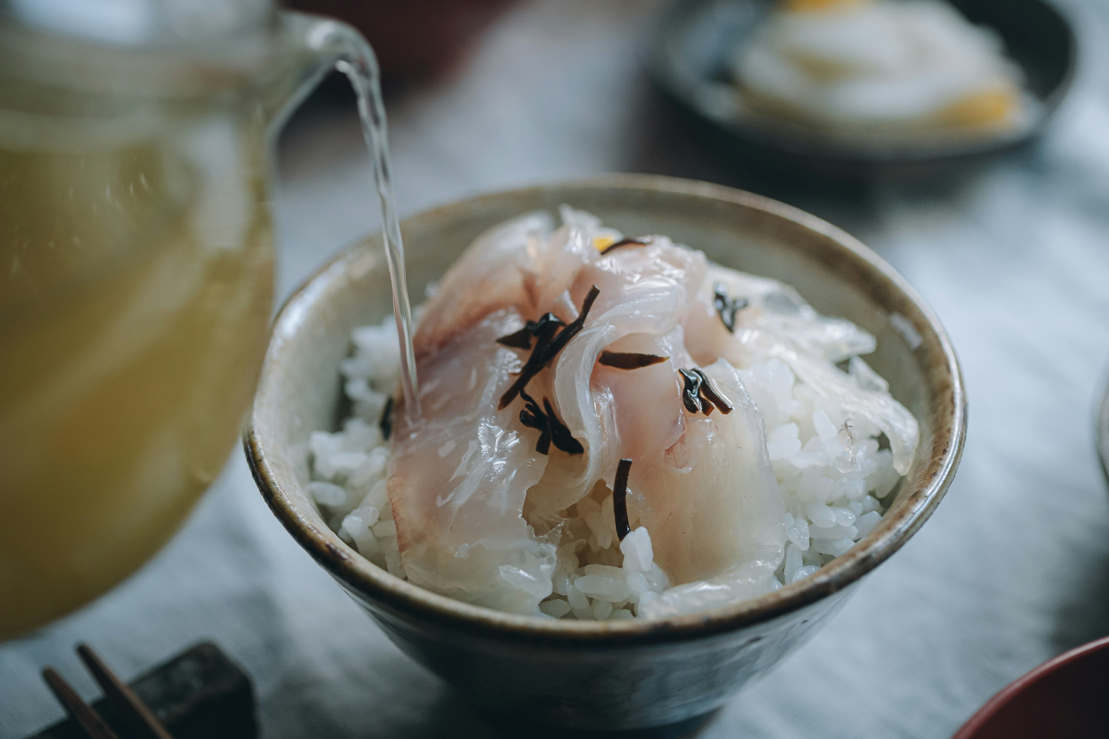 Sebuah mangkuk nasi dengan sashimi segar yang sedang dituangkan teh