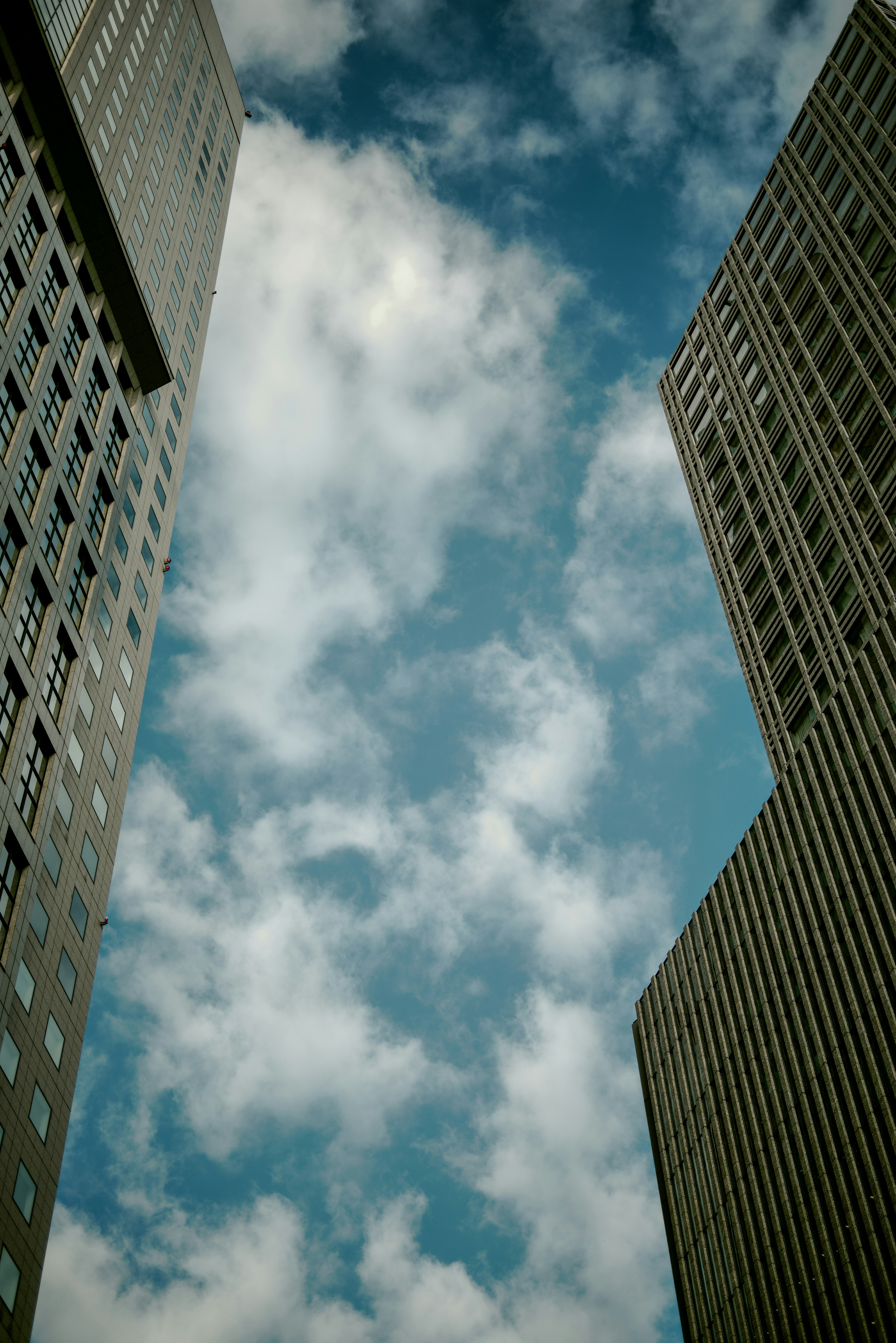 View of blue sky and clouds between tall buildings