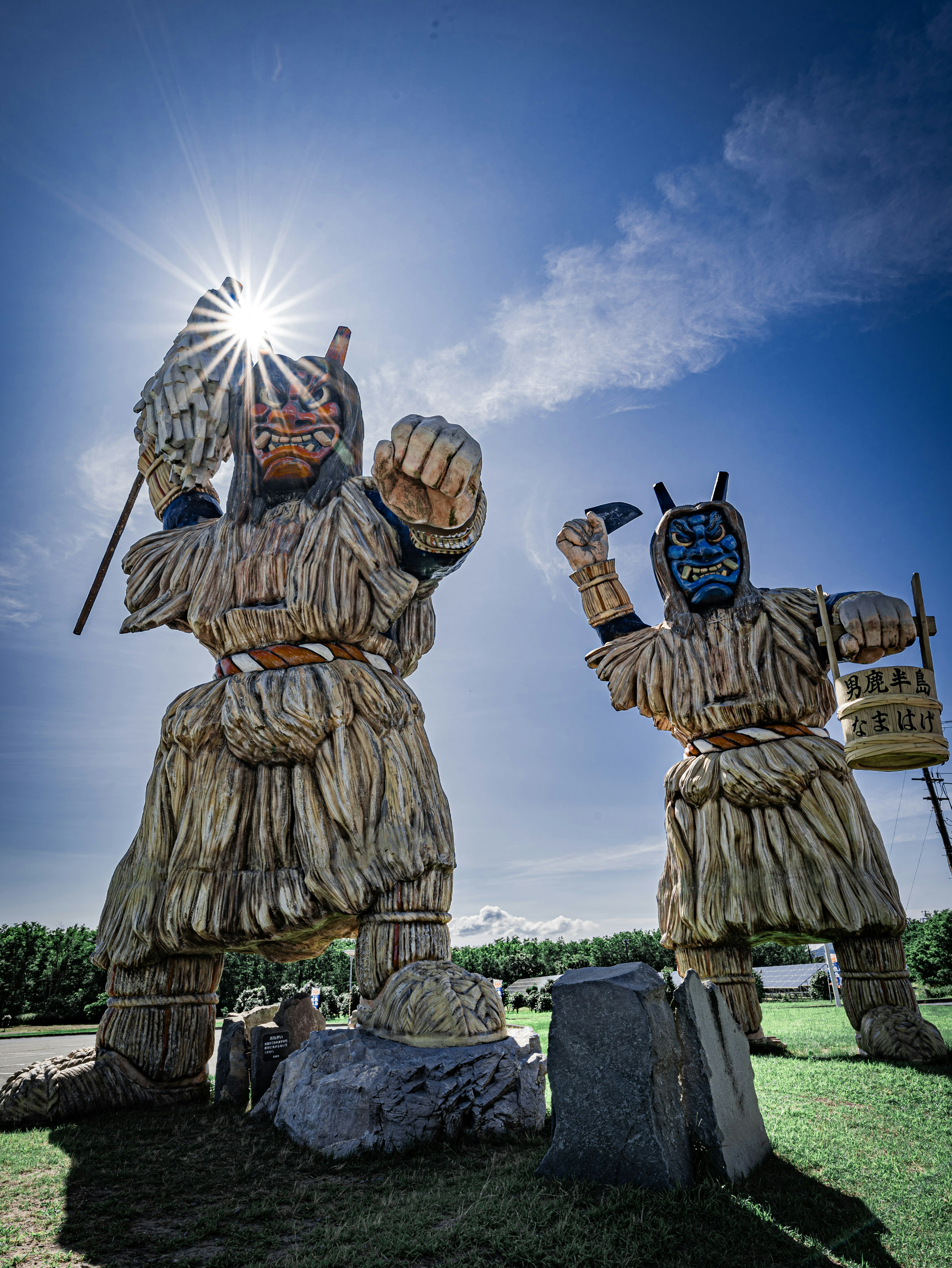 Two giant wooden sculptures standing under a blue sky