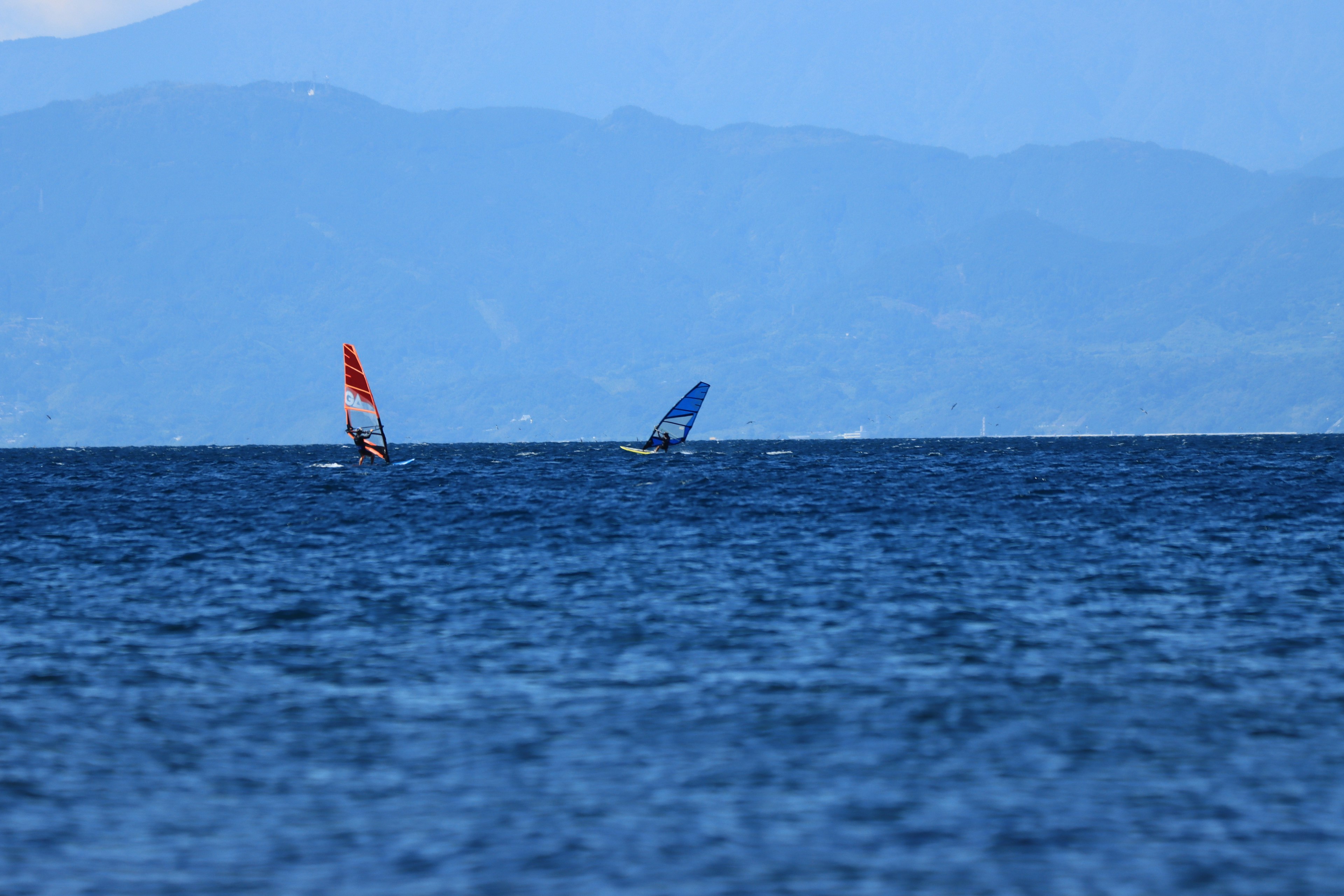 Zwei Windsurfboards gleiten über ein blaues Meer