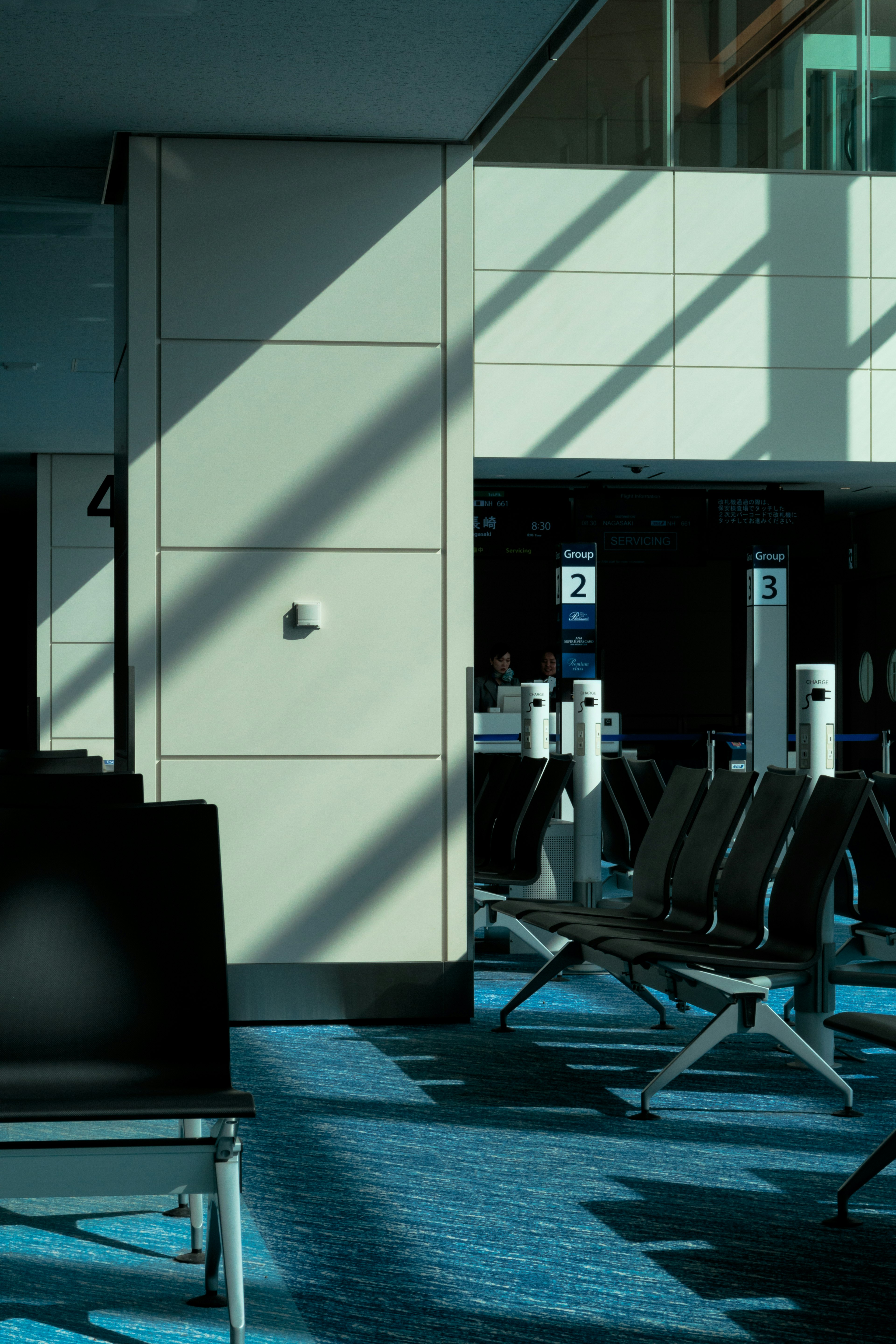 Photo of an airport waiting area featuring blue carpet and prominent shadows