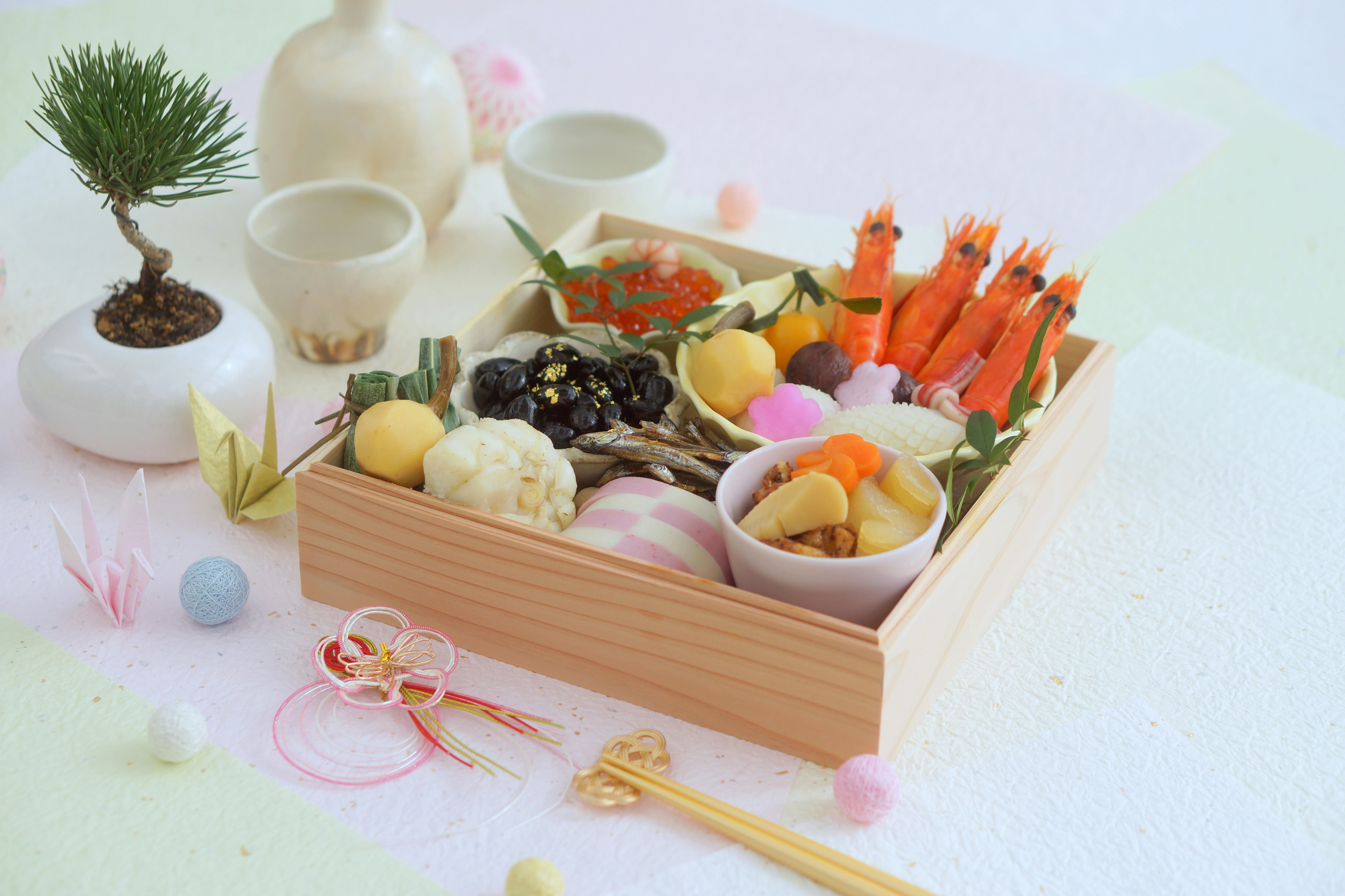 A wooden box filled with colorful Japanese cuisine and traditional decorations