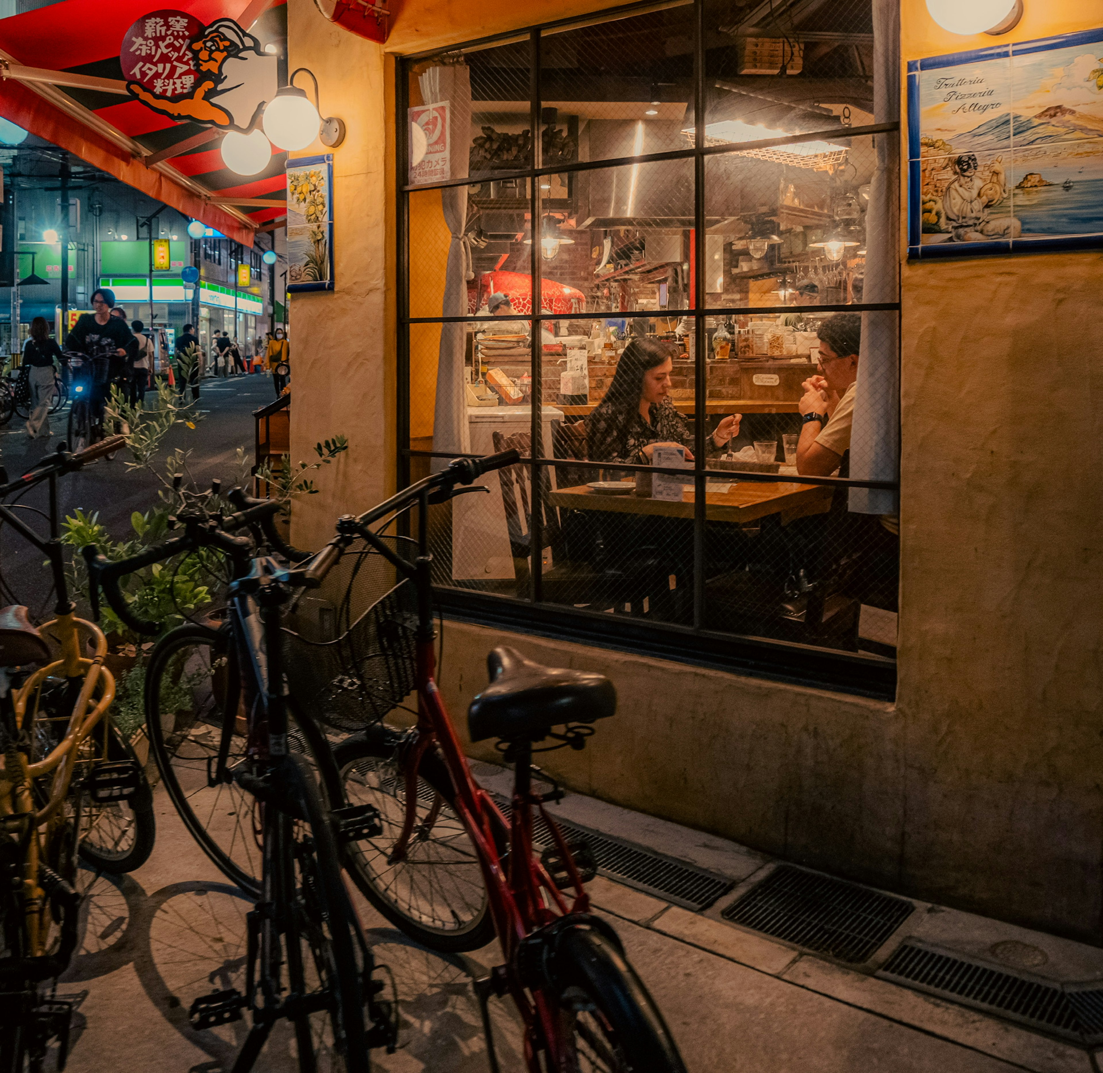 Two women conversing in a cafe seen through a window with bicycles parked outside