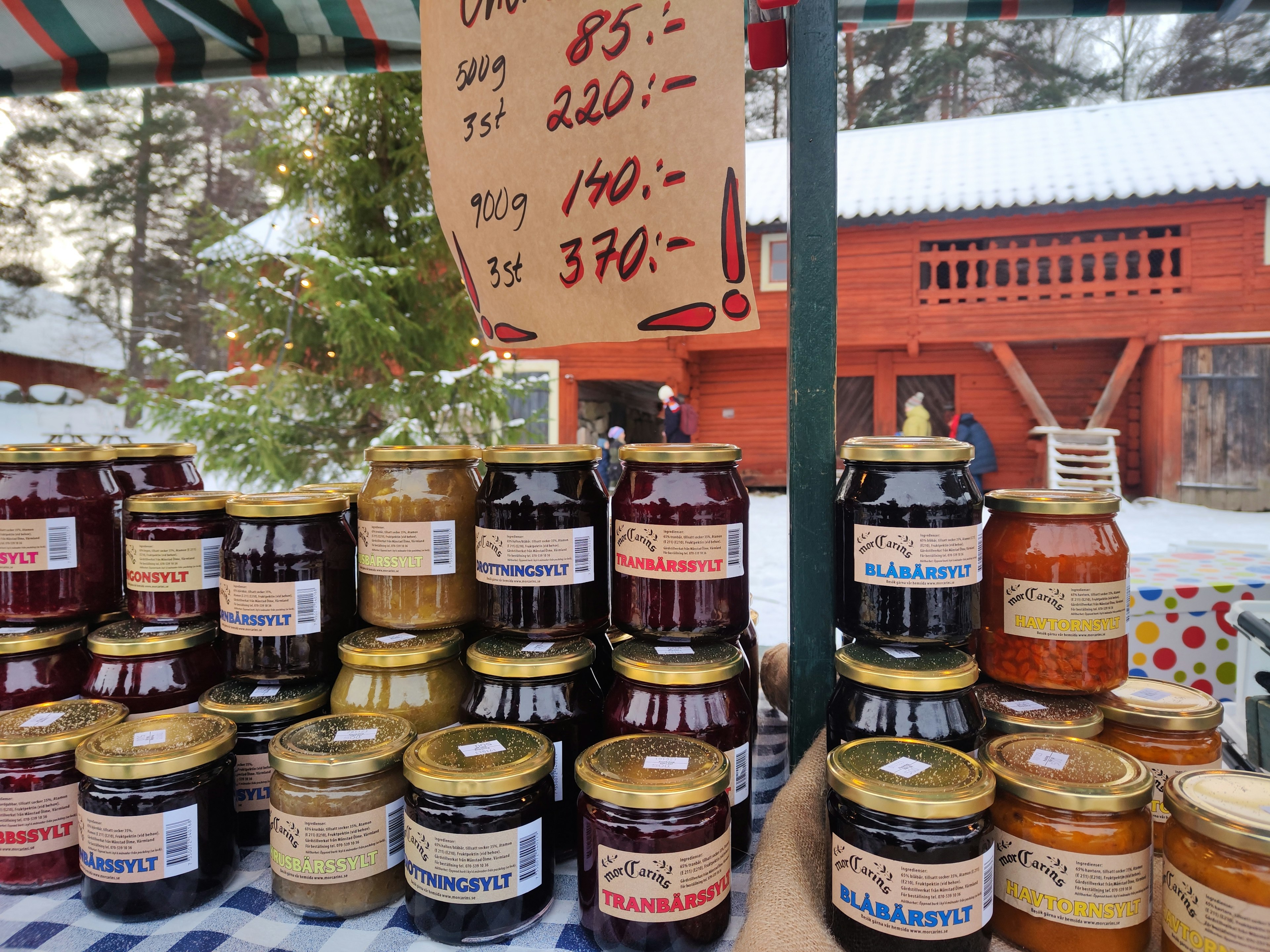 A colorful display of jam jars at a market stall with price tags