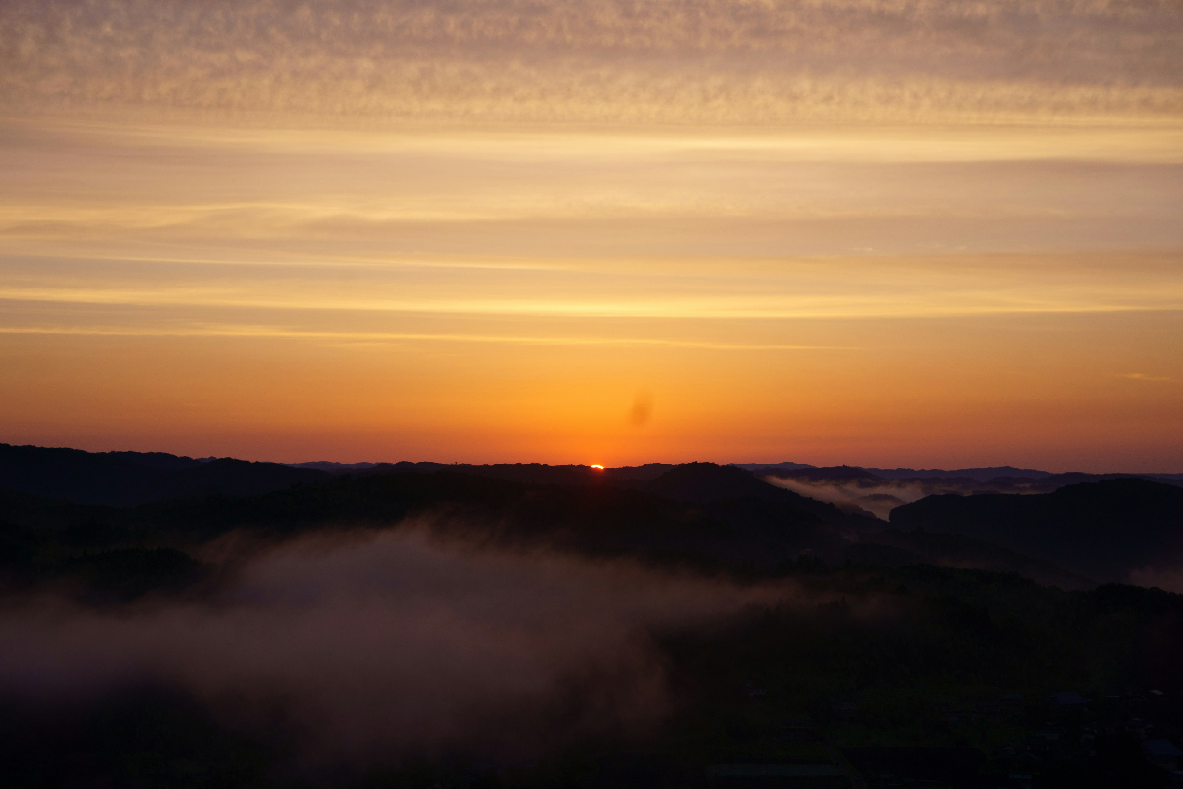 Hermoso amanecer que surge entre montañas con nubes suaves