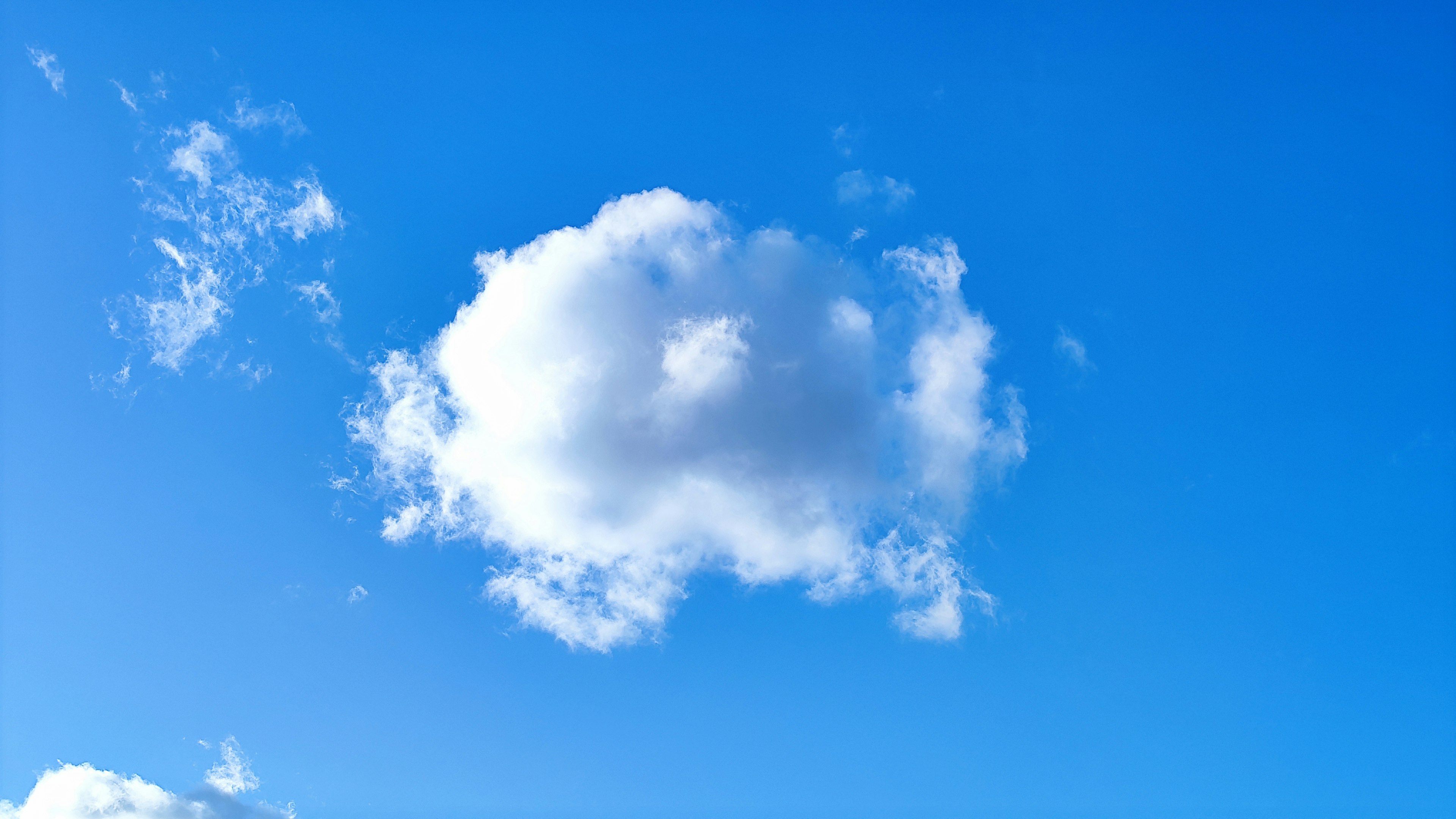 Eine einzelne weiße Wolke schwebt in einem hellblauen Himmel