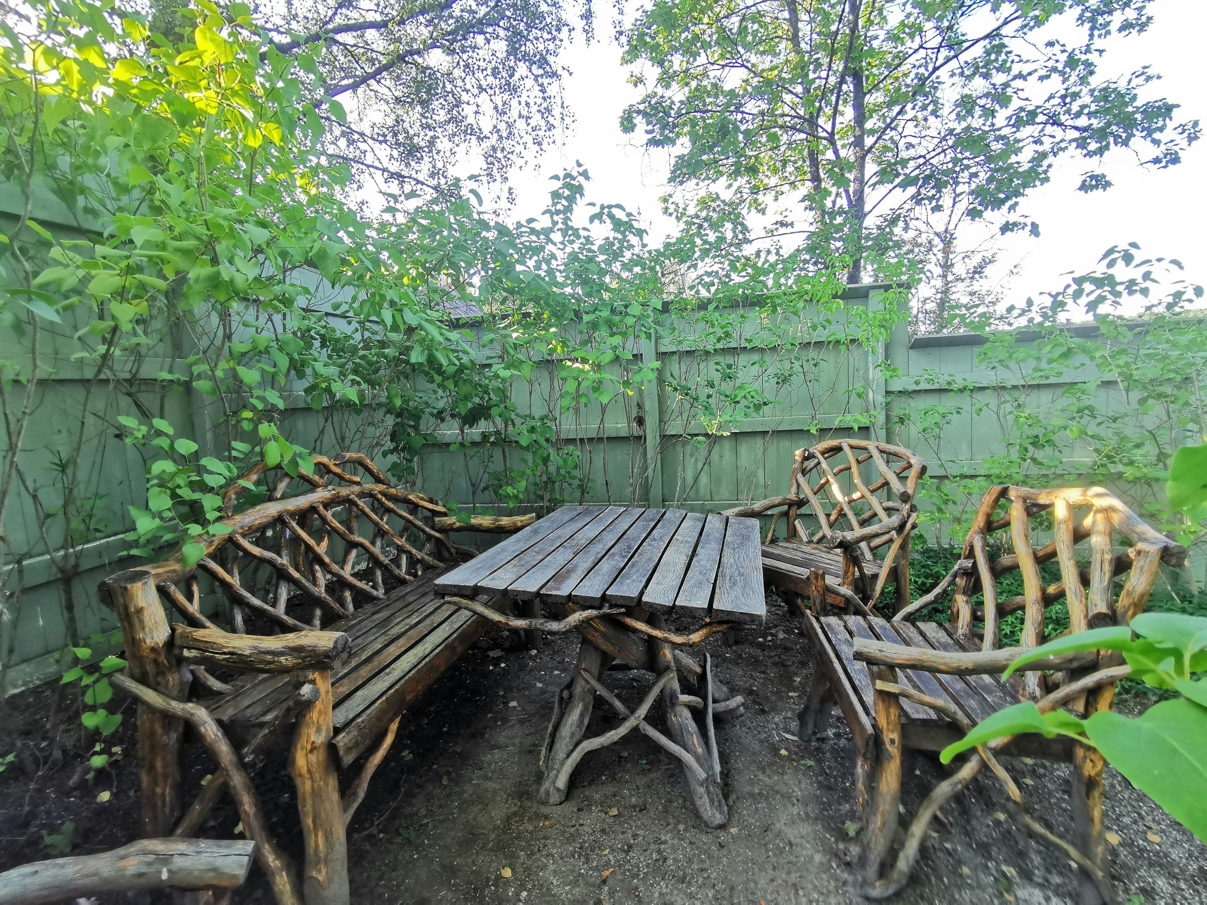 Un espacio de jardín tranquilo con mesa y sillas de madera hechas de materiales naturales