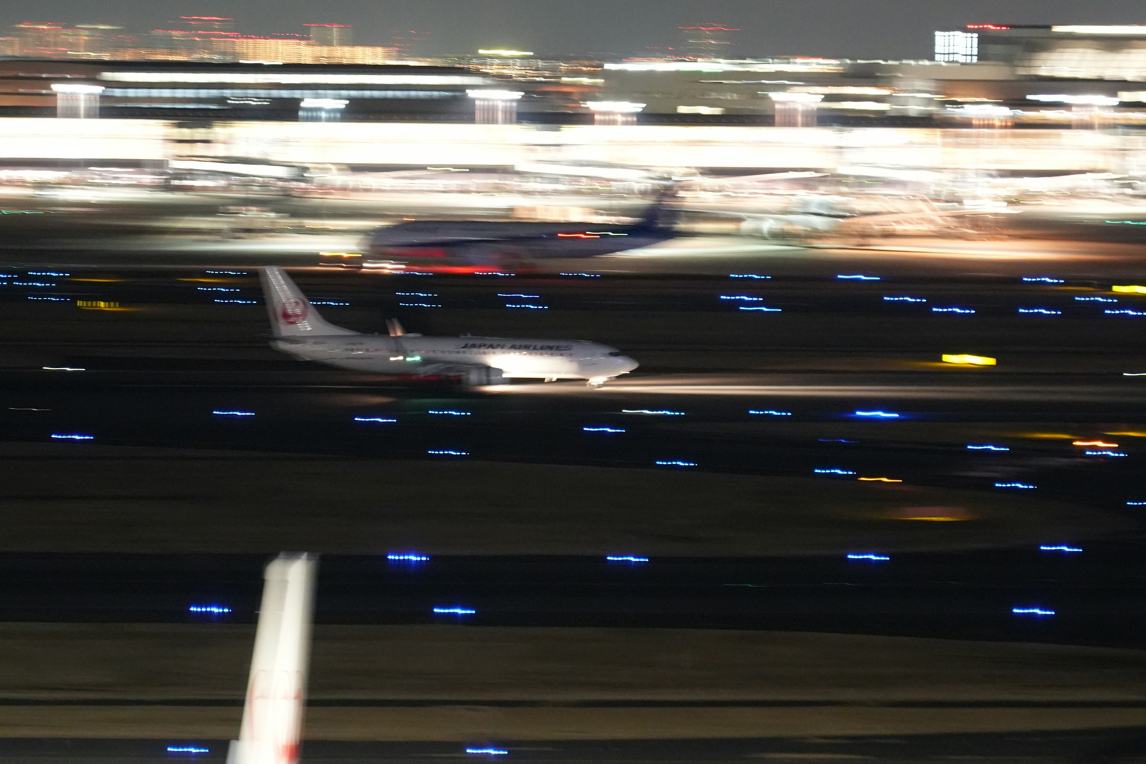 夜の空港で滑走路を滑走する飛行機のぼやけた画像