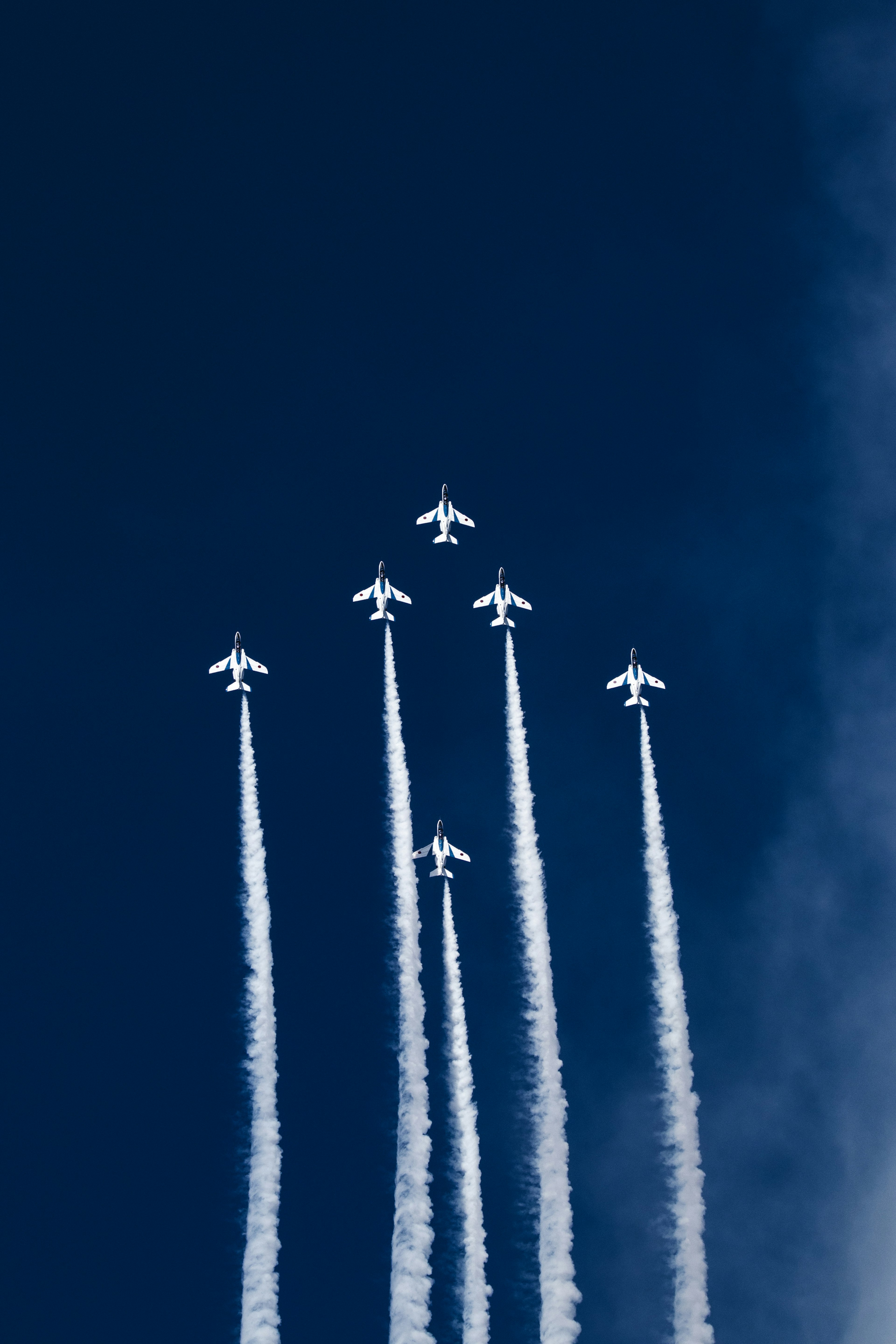 Formación de aviones blancos ascendiendo en un cielo azul