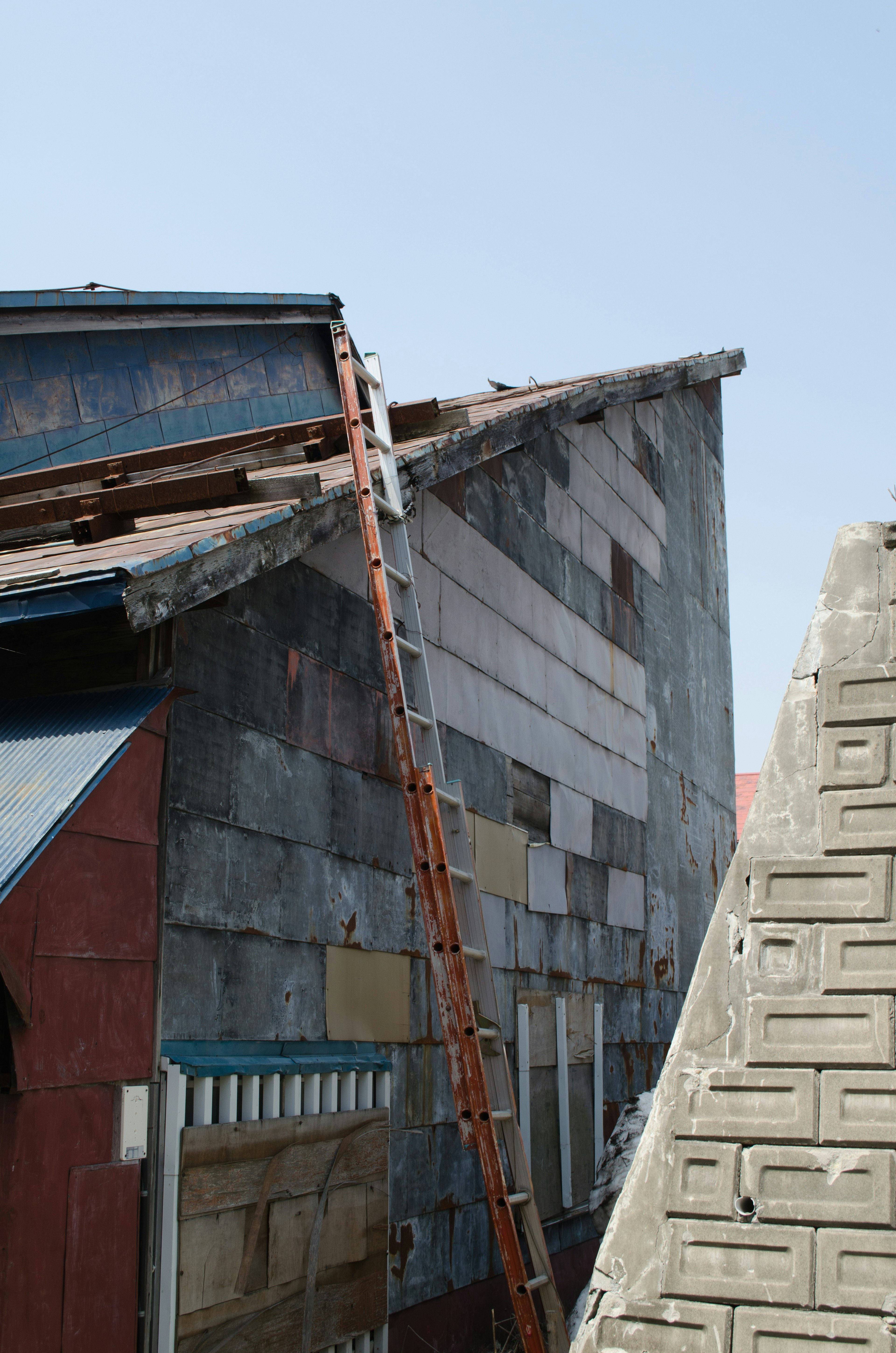 Part of a building showing a slanted roof and a ladder