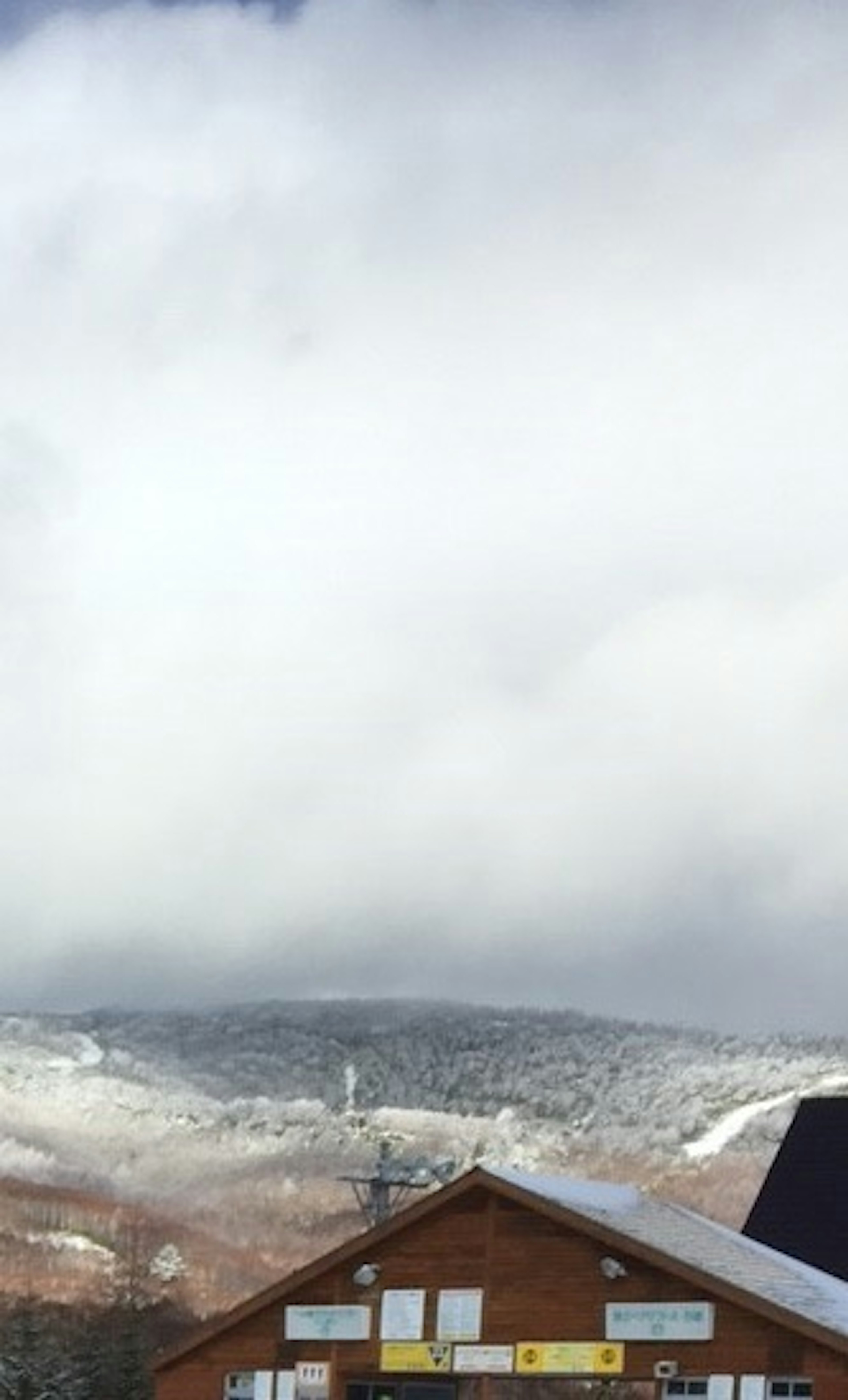 Una baita con una montagna innevata e nuvole sullo sfondo