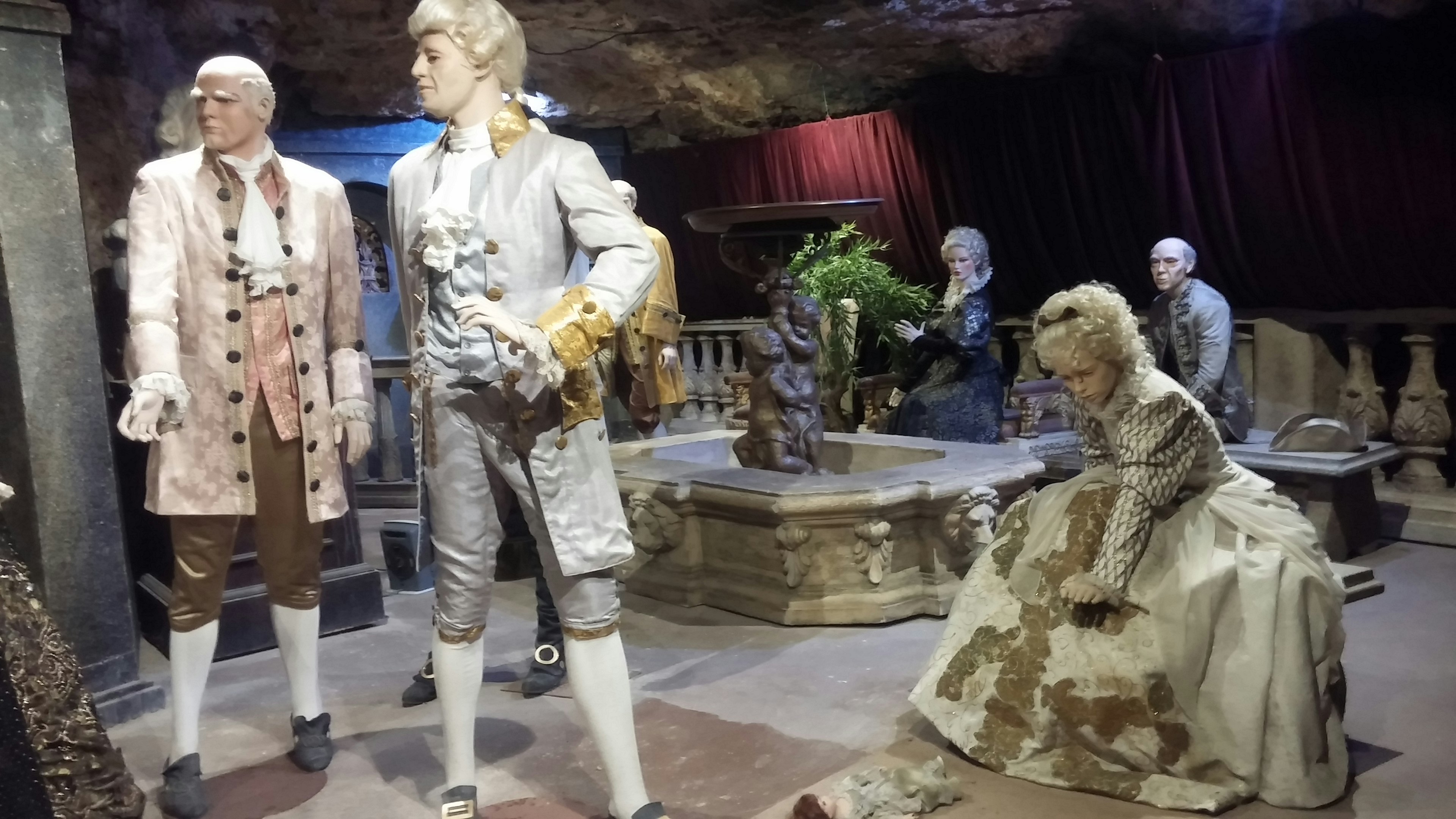 Scene of mannequins in historical costumes displayed in a dimly lit room