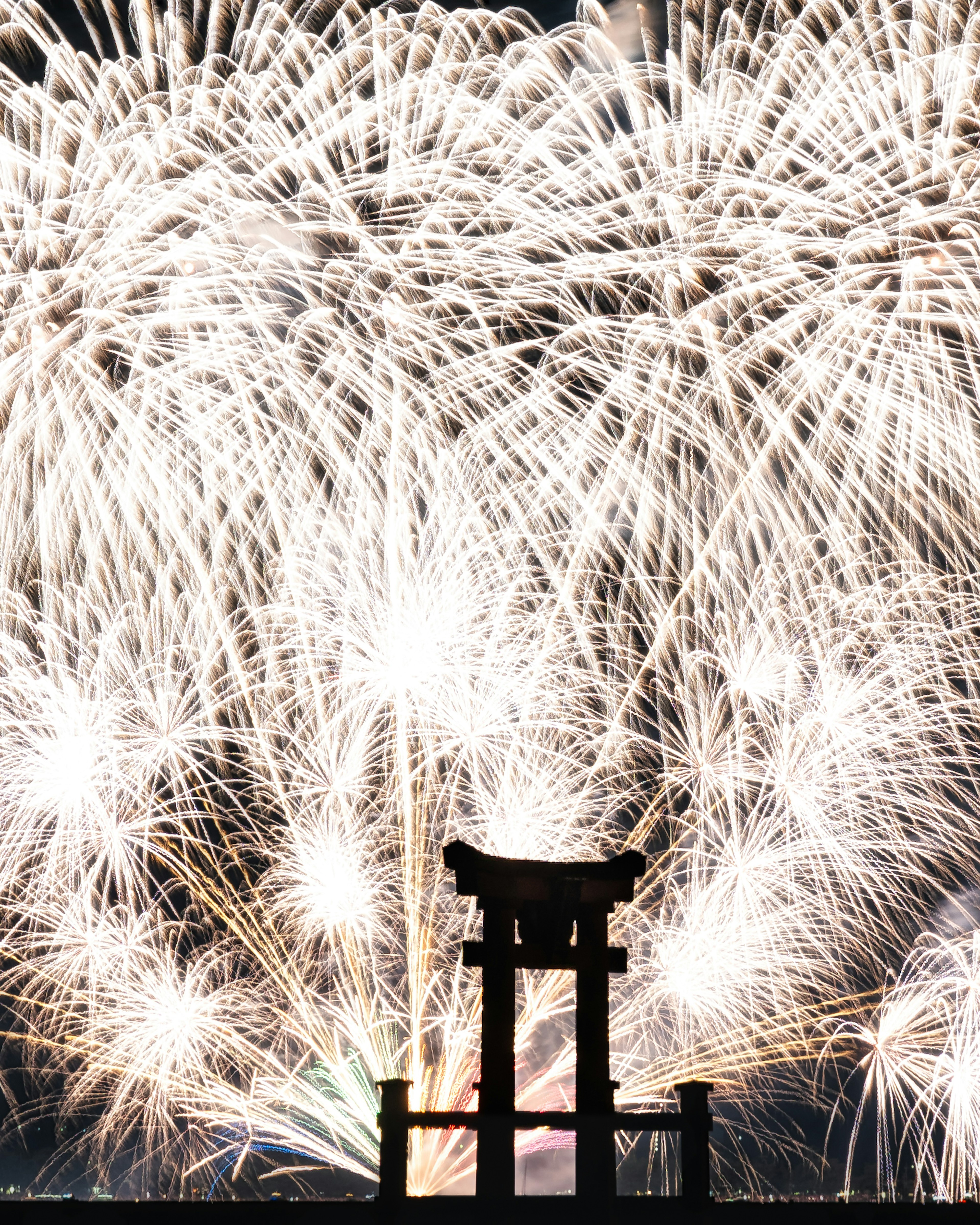 Silhouette of a torii gate against a backdrop of fireworks