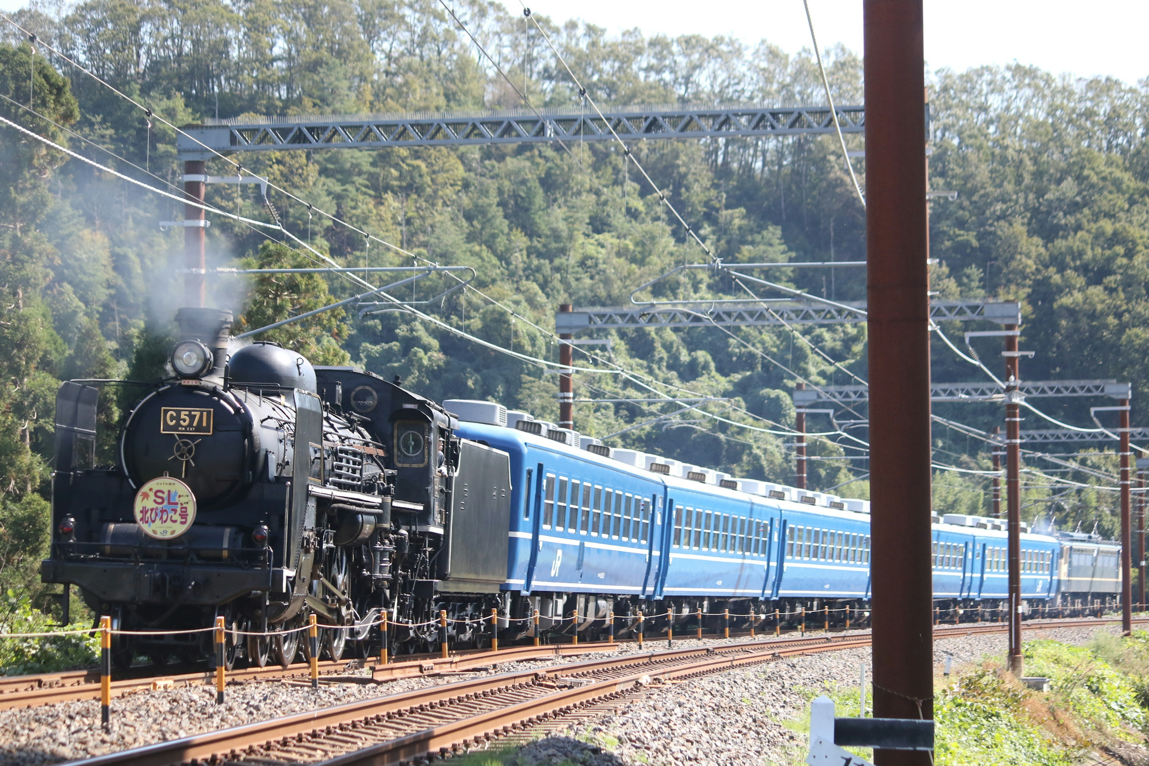 青い列車を牽引する蒸気機関車が線路を走る風景