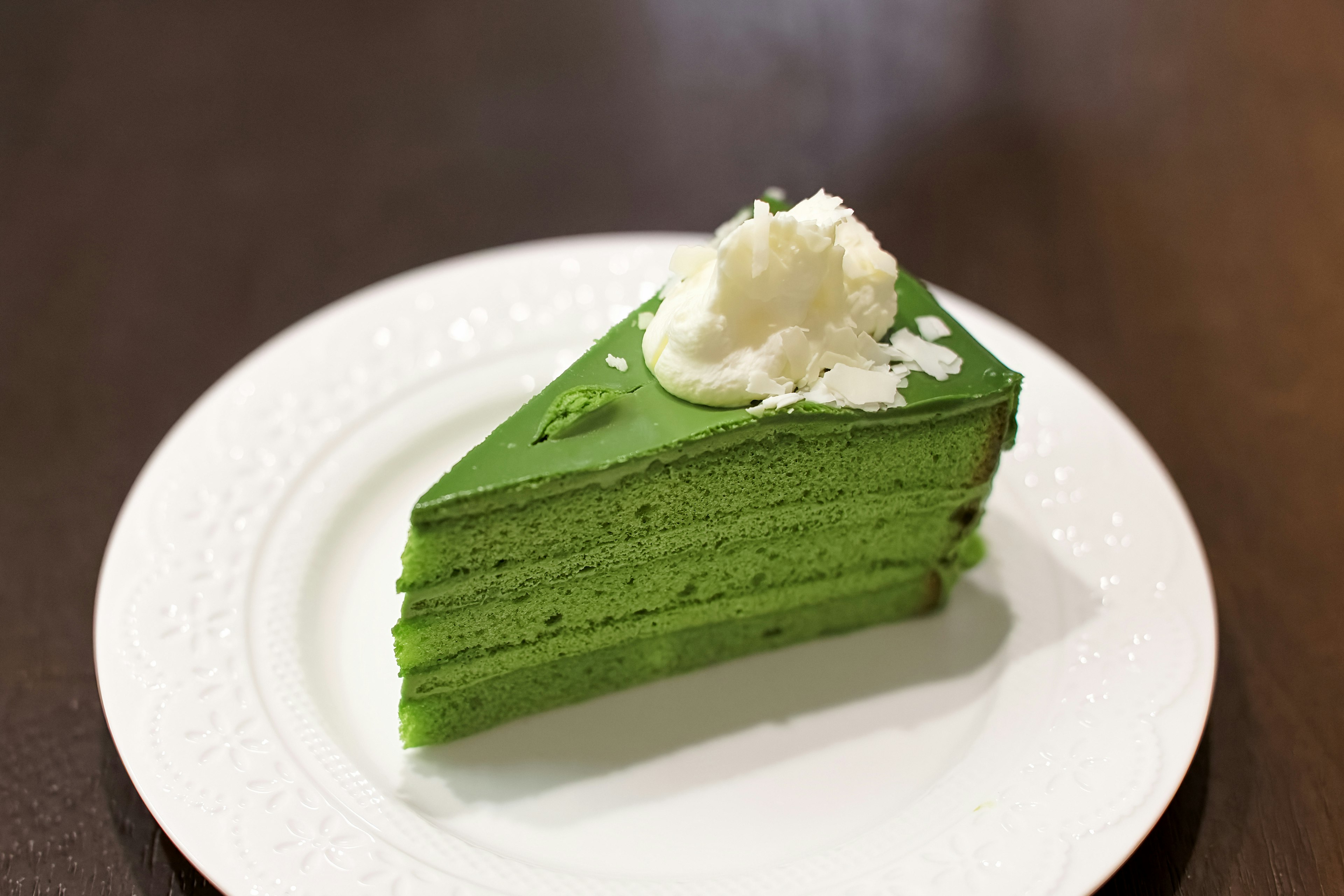 緑色の層のケーキにホイップクリームがトッピングされたデザート