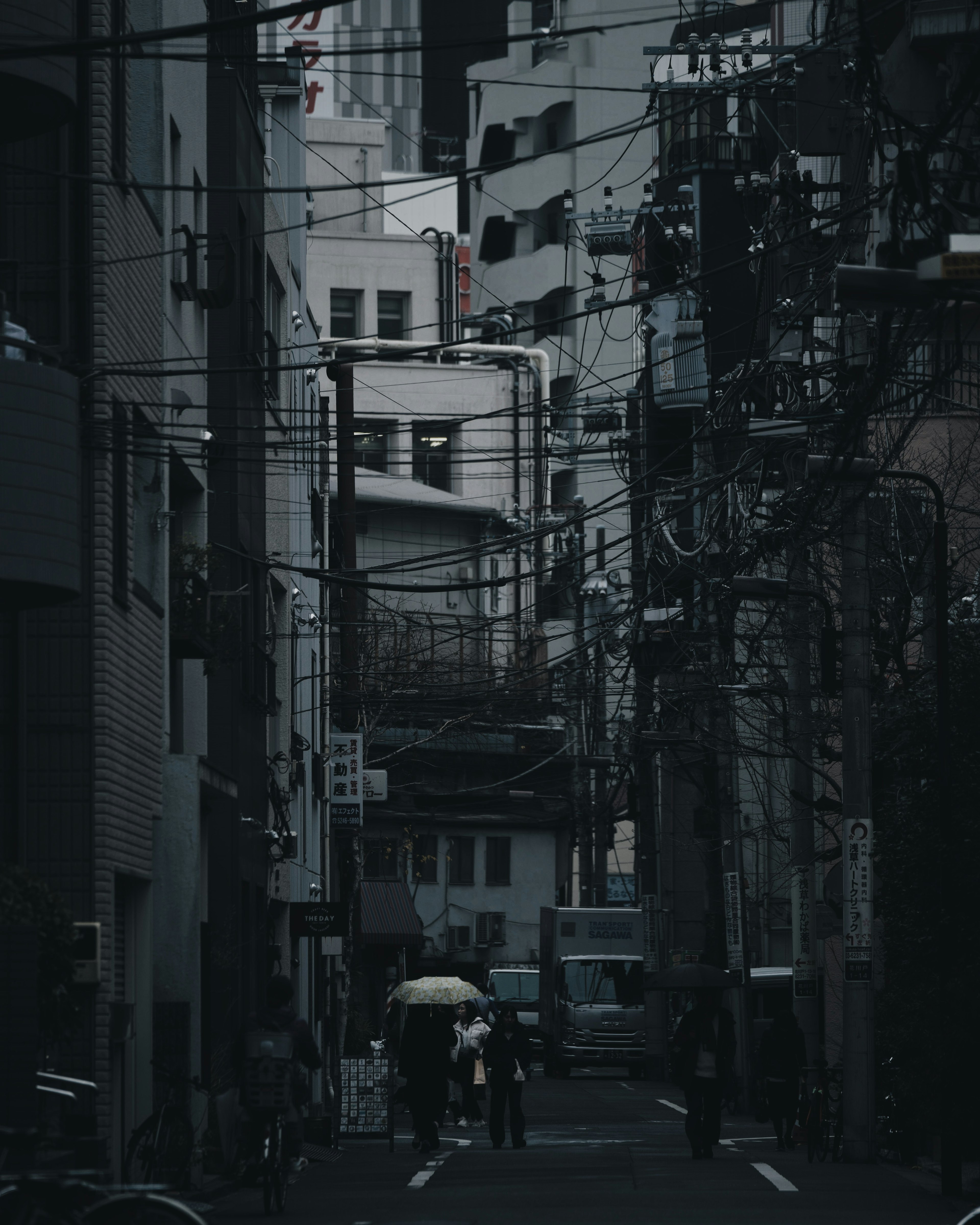 Personas caminando con paraguas en un callejón oscuro