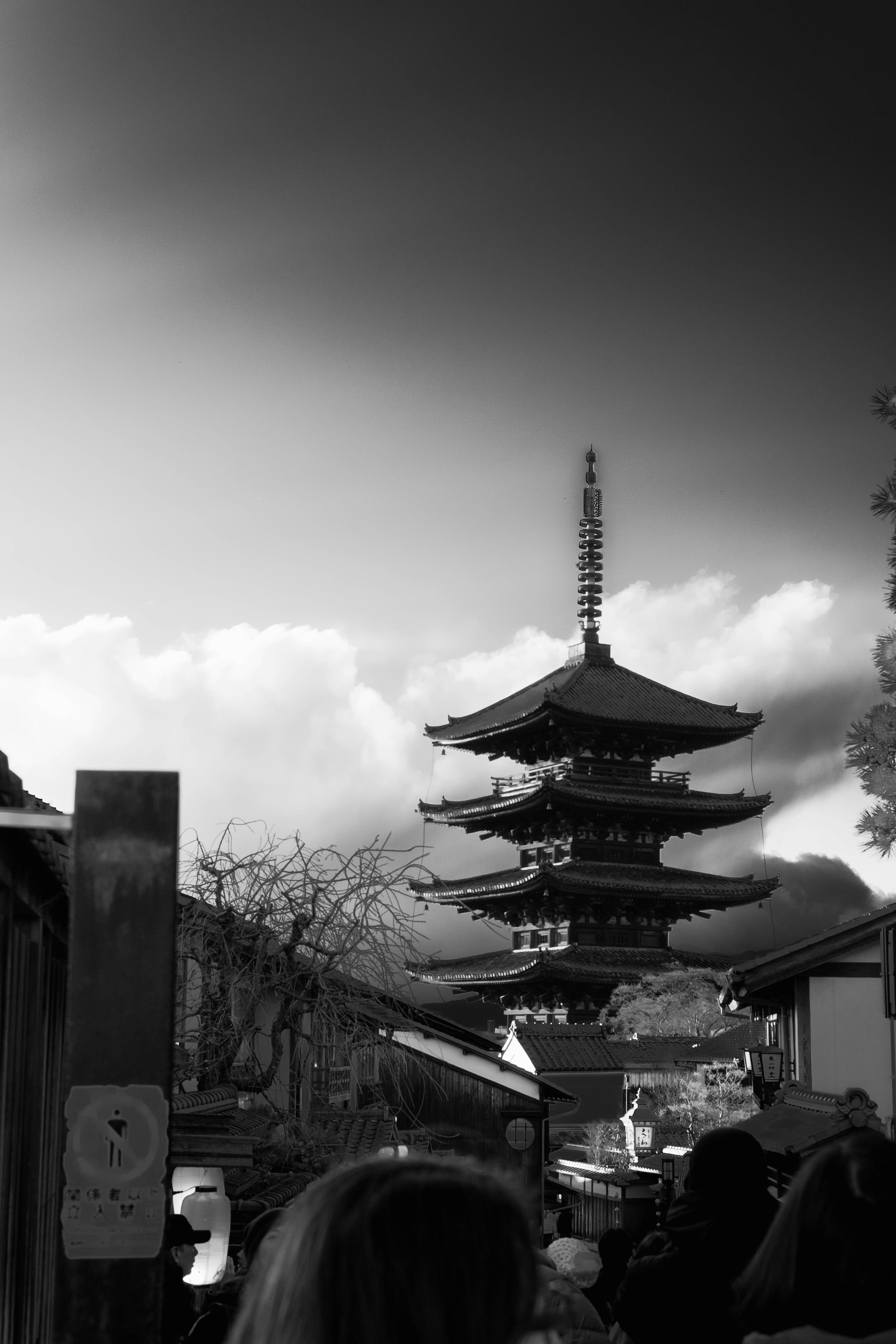 A black and white view of a pagoda with clouds in the background