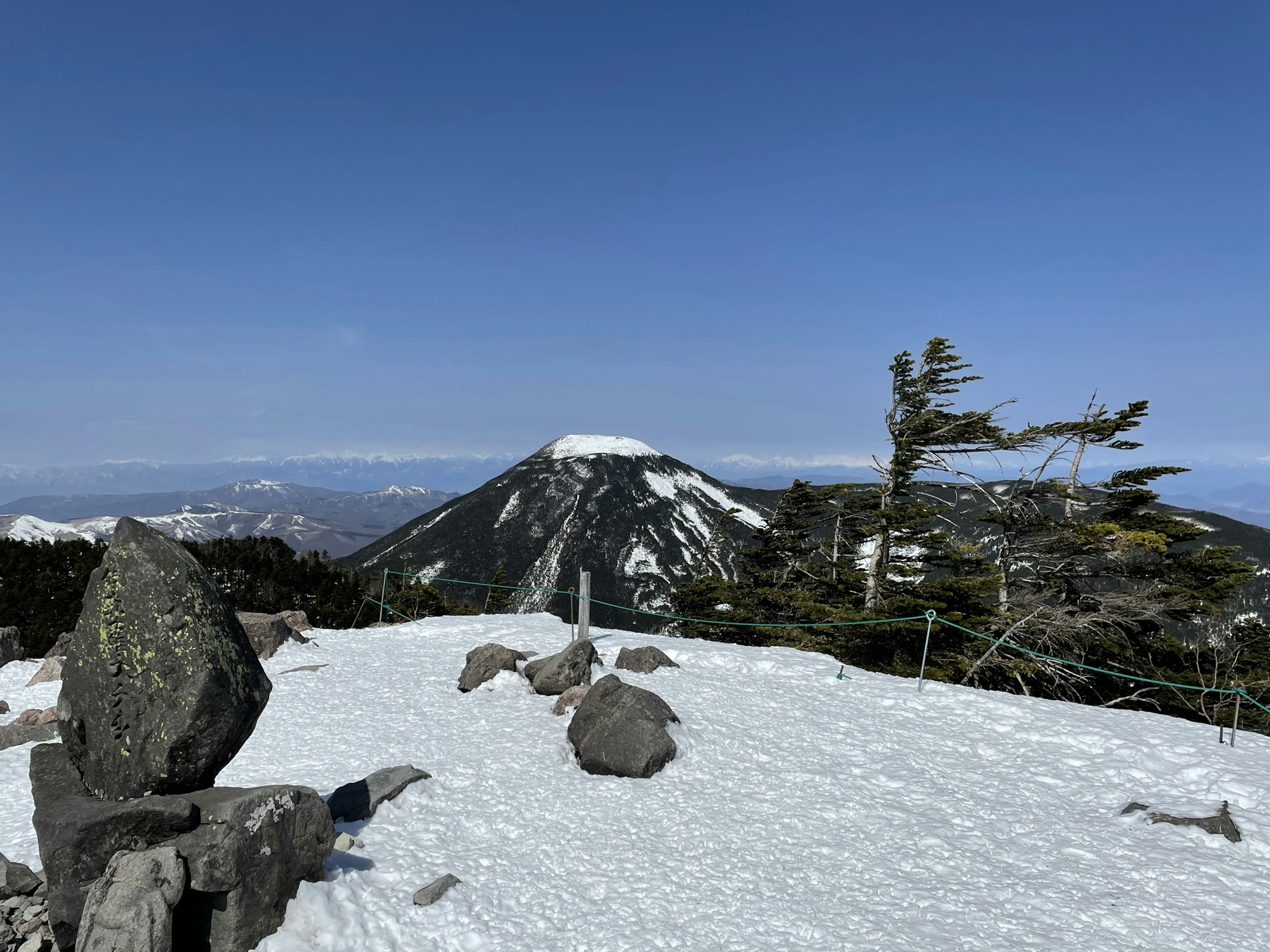 View from a snowy mountain peak under a clear blue sky