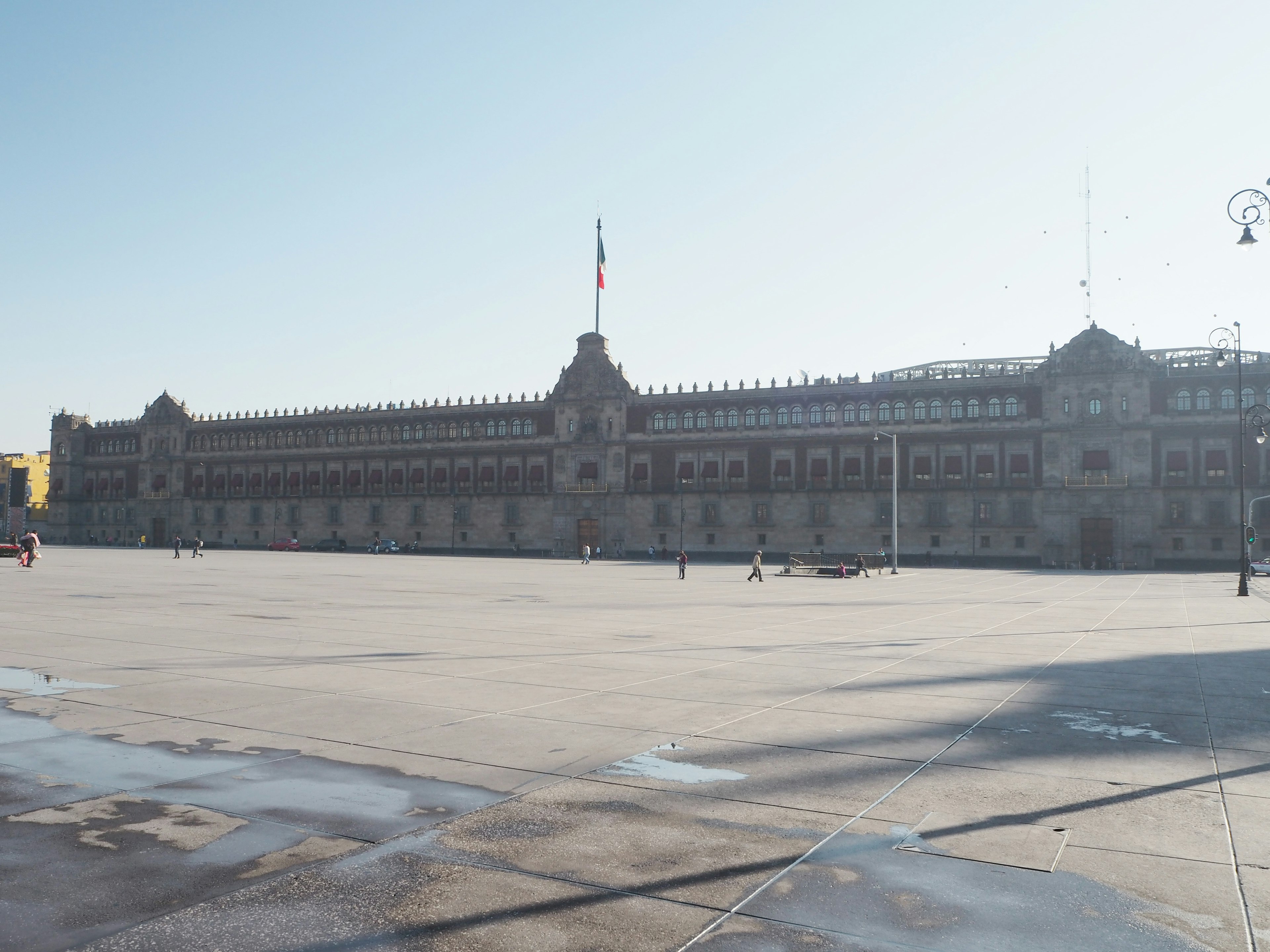 Fachada de un gran edificio frente a la plaza con una bandera nacional