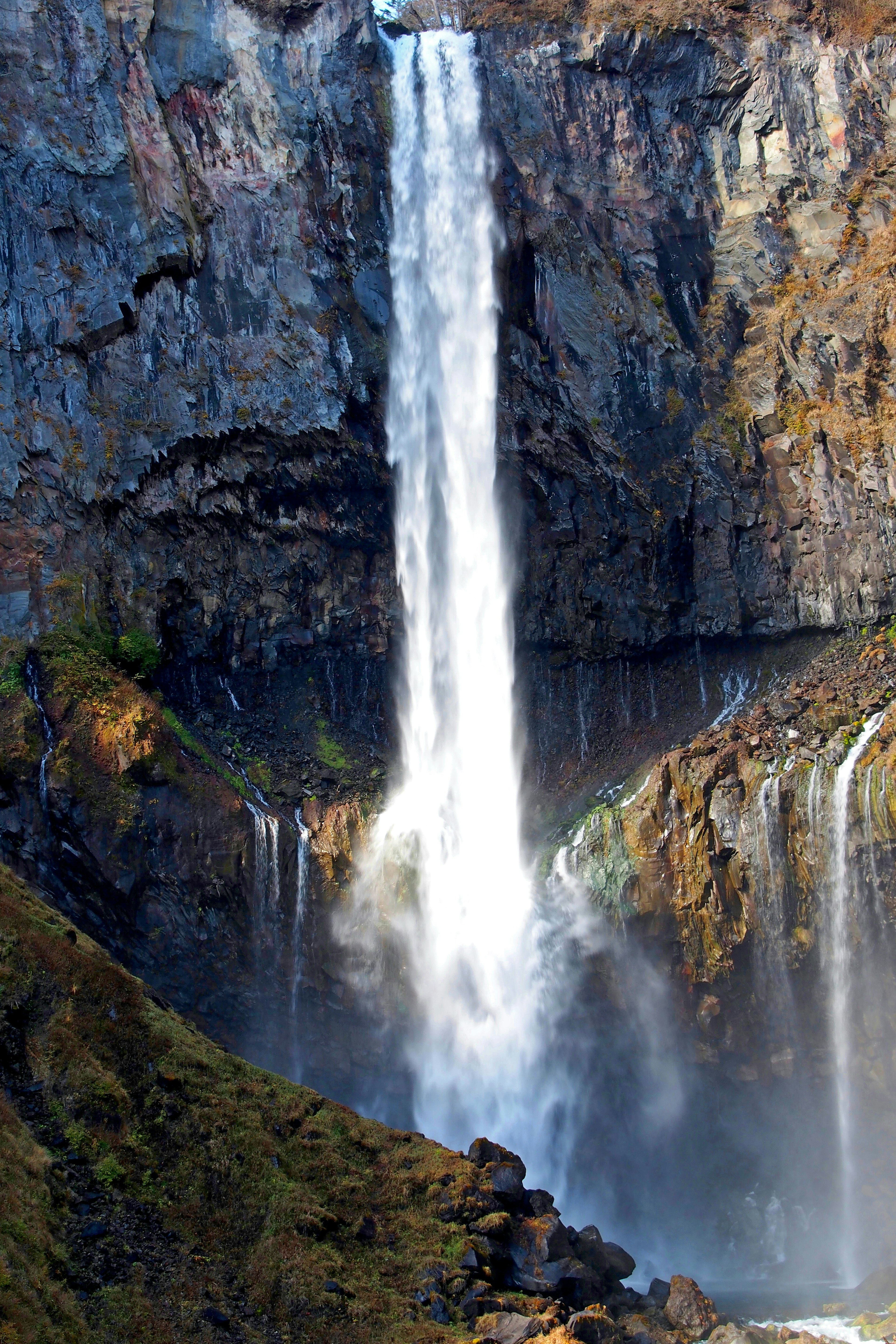 A majestic waterfall cascading down a rocky cliff surrounded by lush greenery