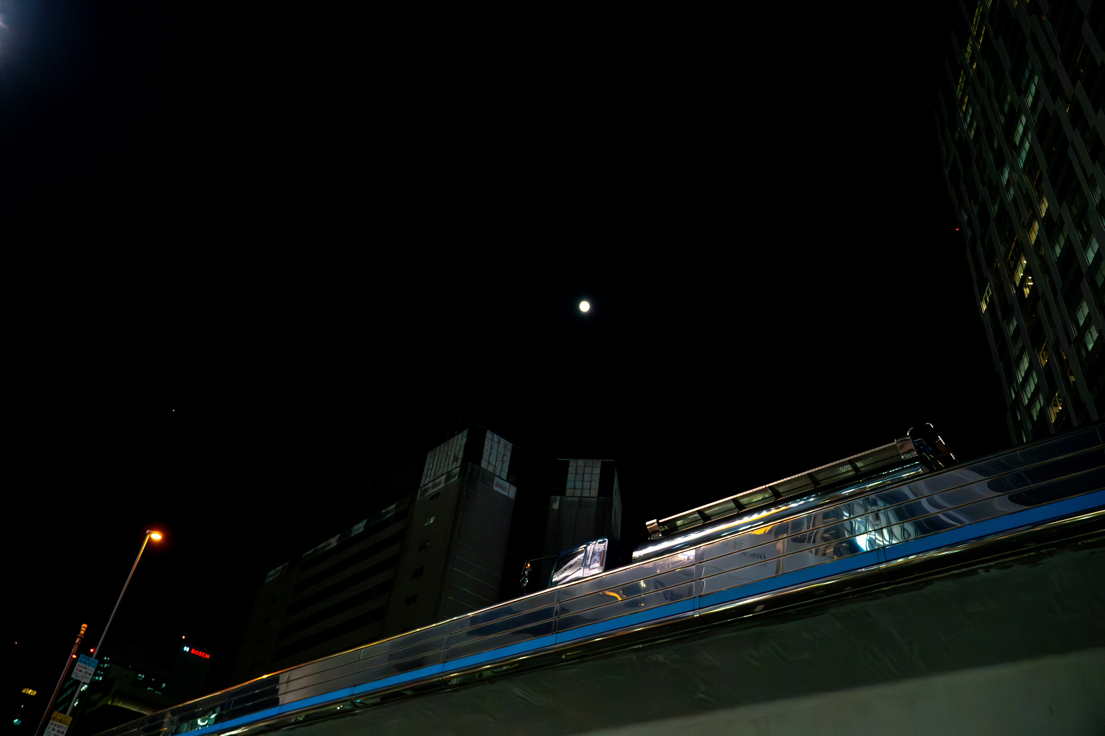 Lune visible dans le ciel nocturne au-dessus des bâtiments de la ville