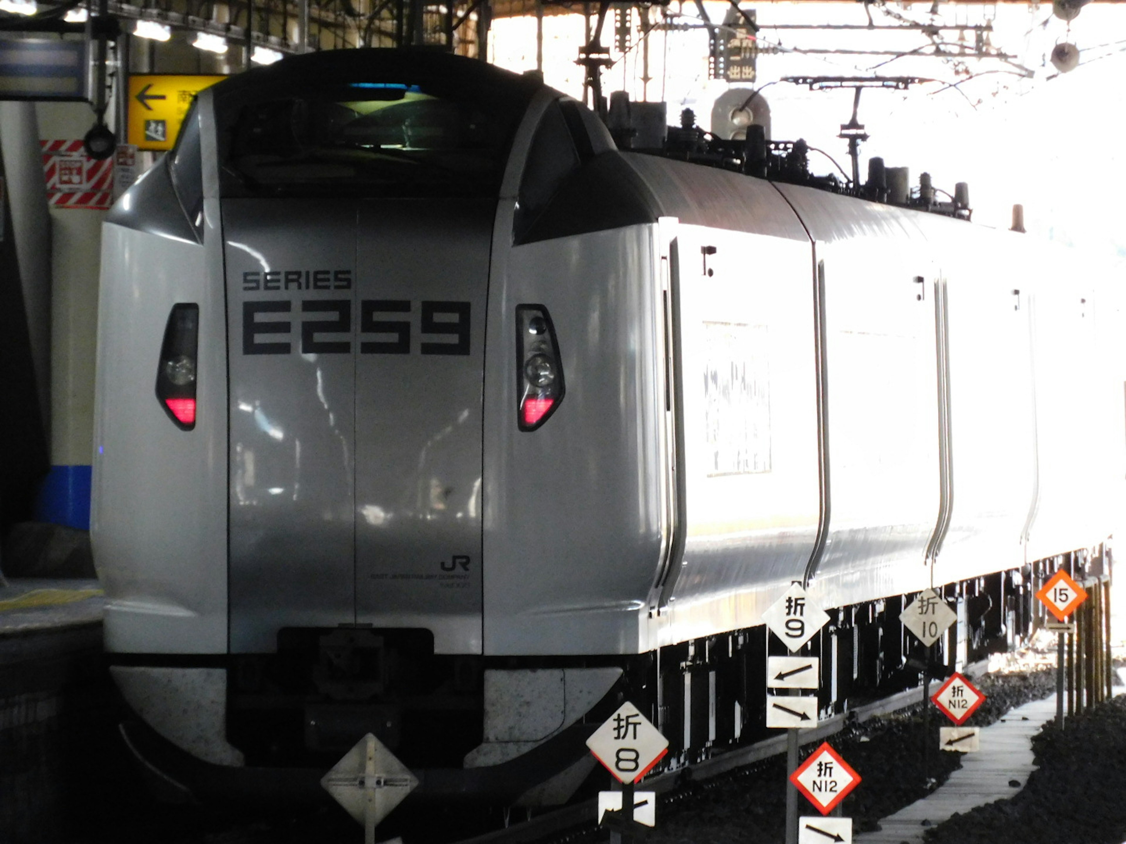 Silver E259 series train parked at a station