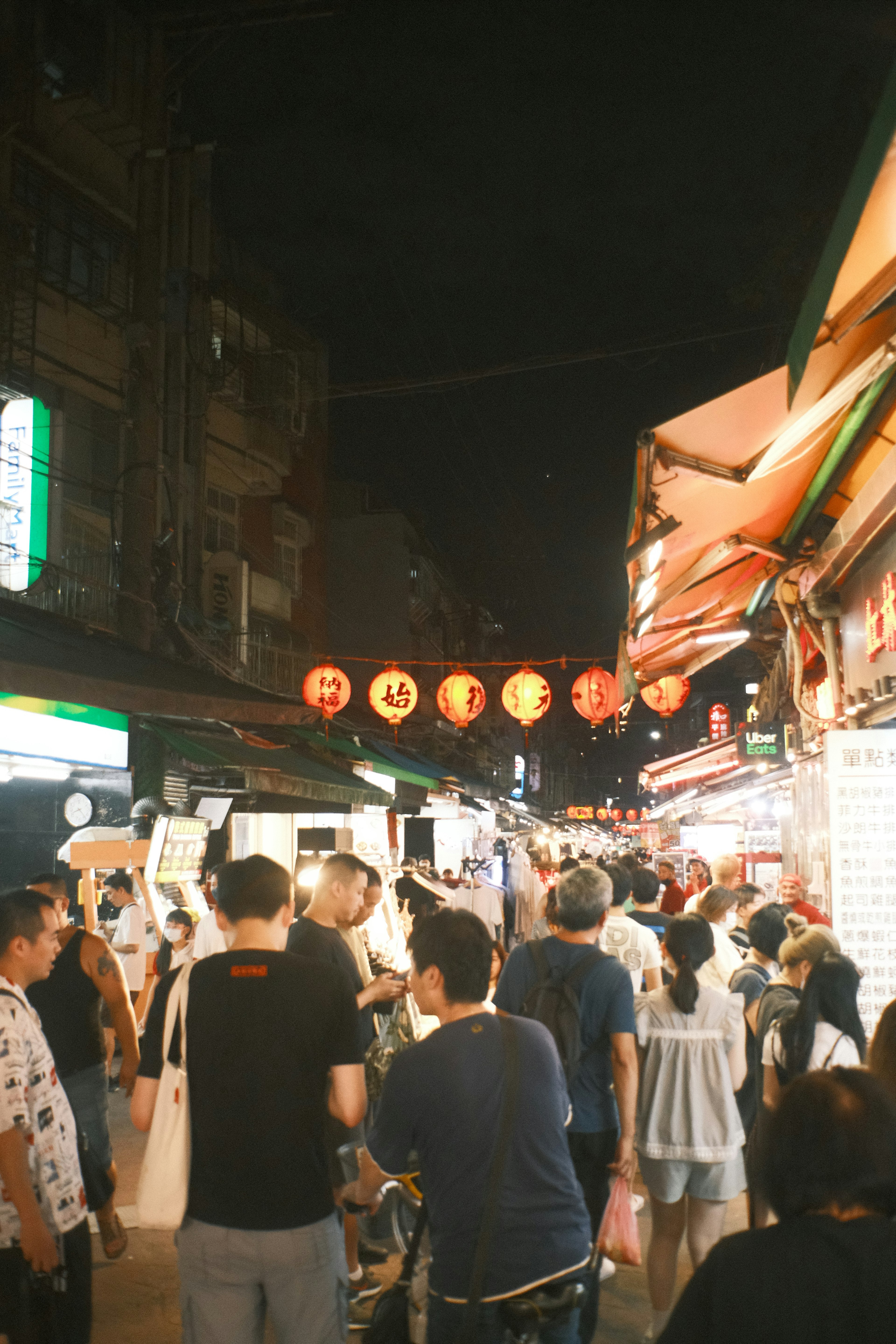 Kerumunan orang di pasar malam dengan lentera merah tergantung