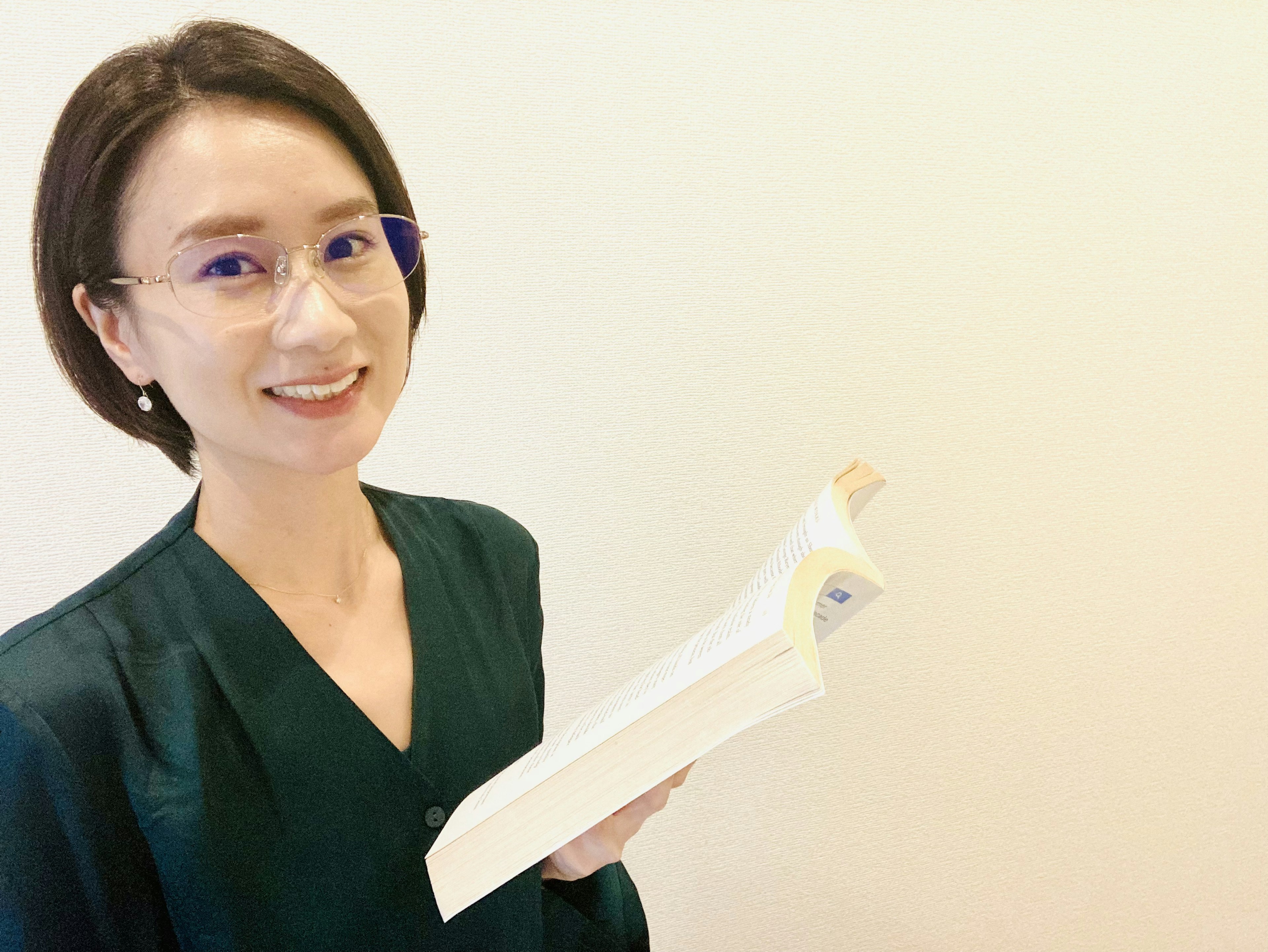 Woman smiling while holding a white book wearing a green outfit