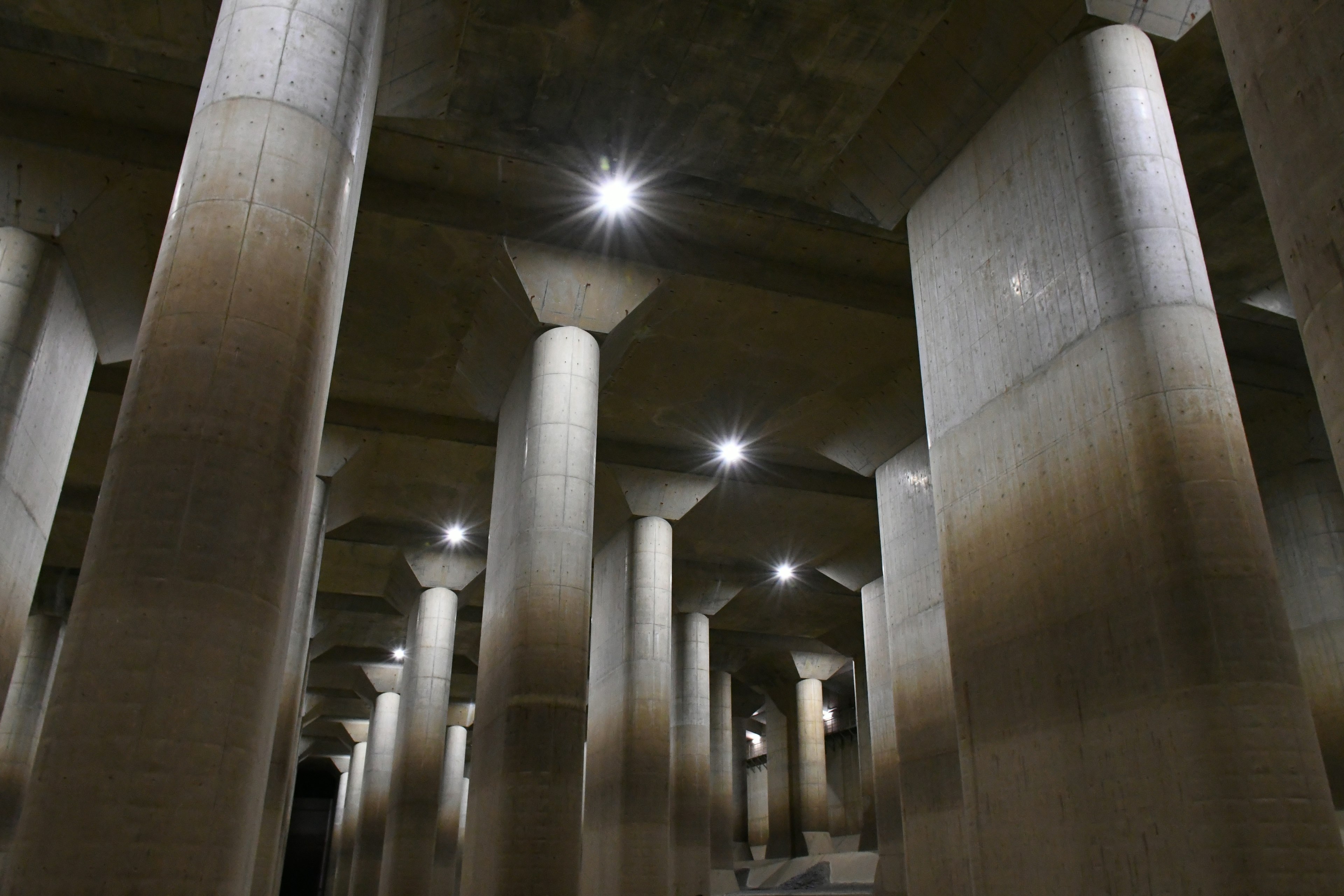 Colonnes en béton dans un espace souterrain éclairé par des lumières