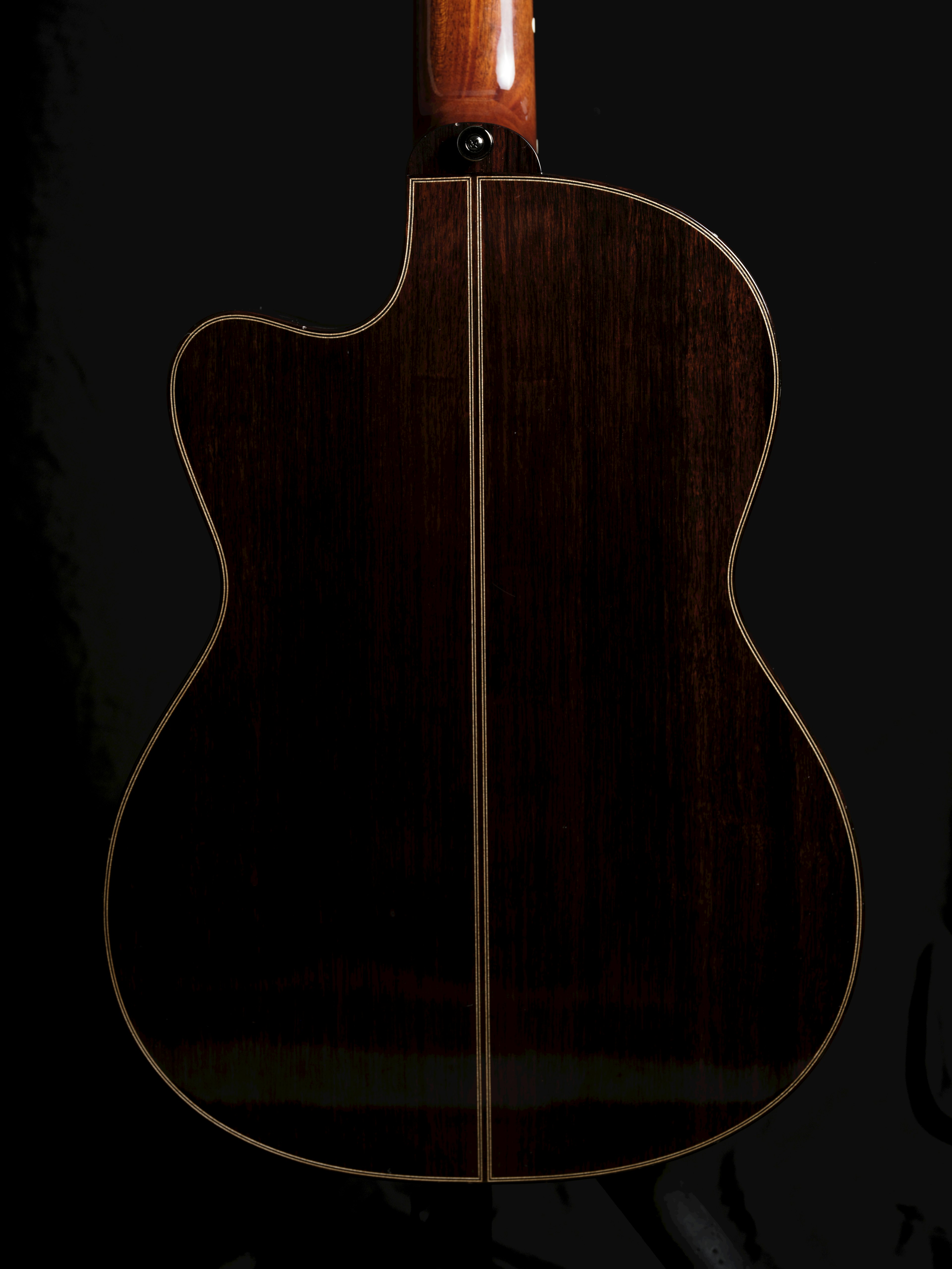 Back view of a beautiful acoustic guitar with rich wood grain on a black background