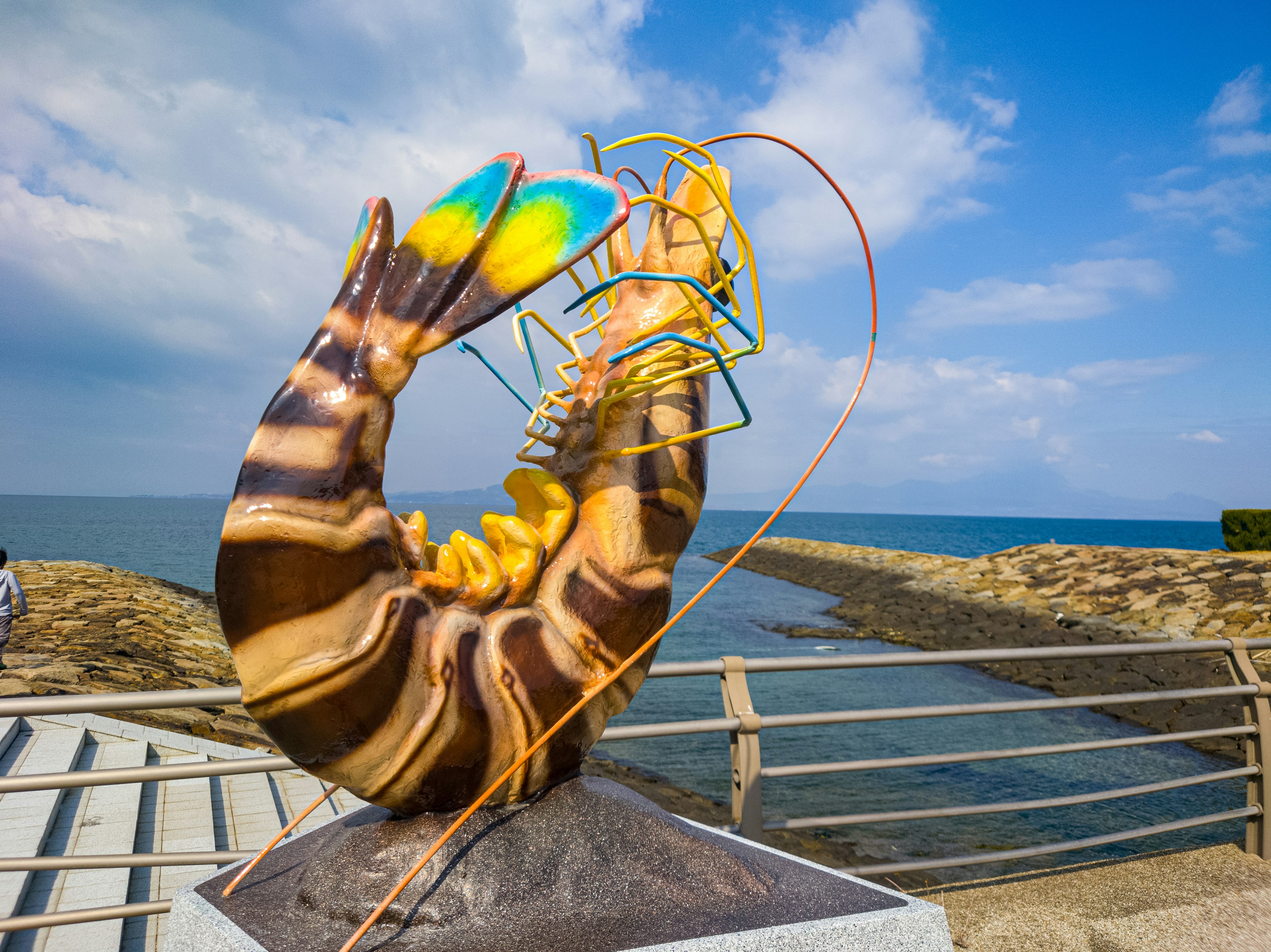 Escultura de camarón colorido en la costa con cielo azul