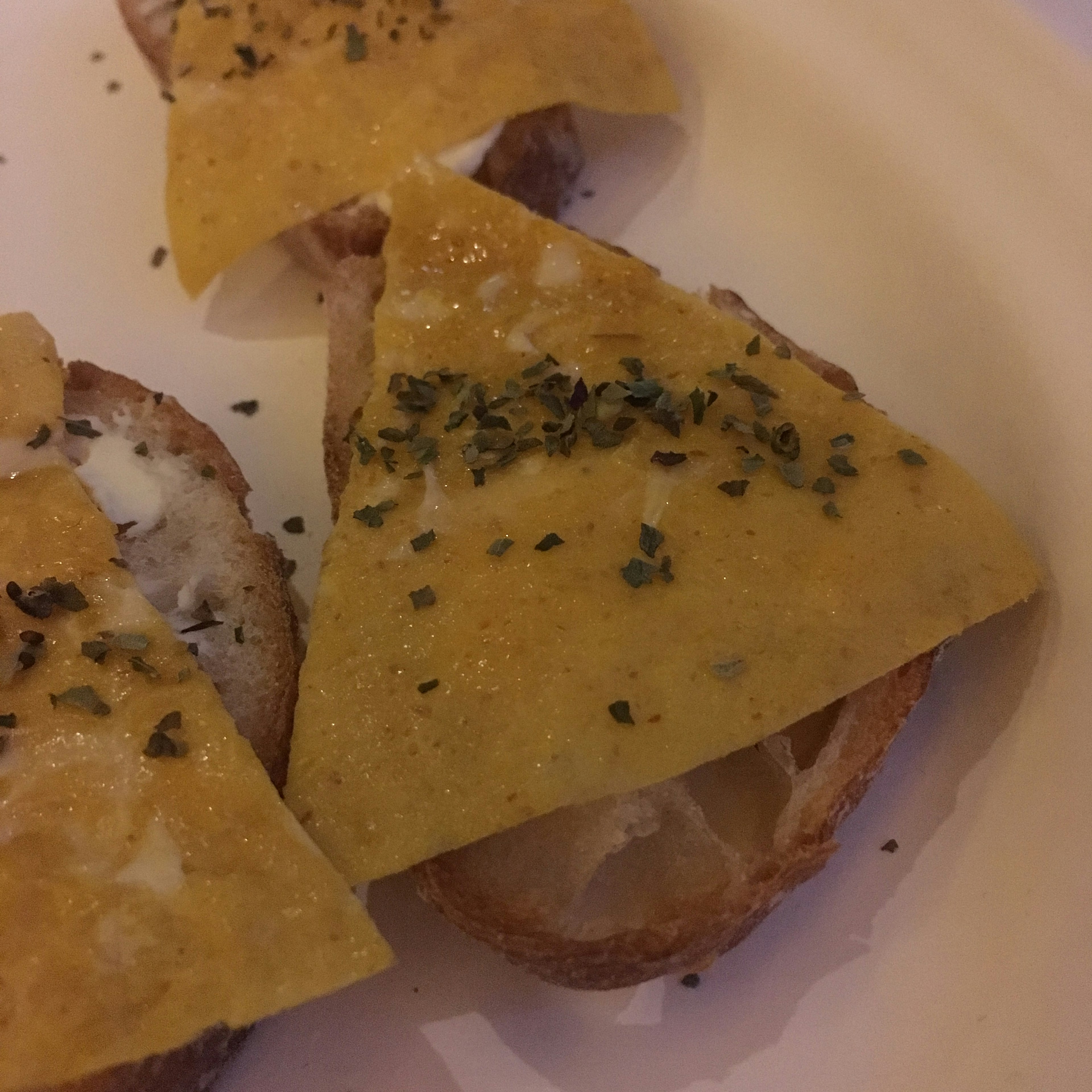 Formaggio triangolare guarnito con erbe su pane tostato