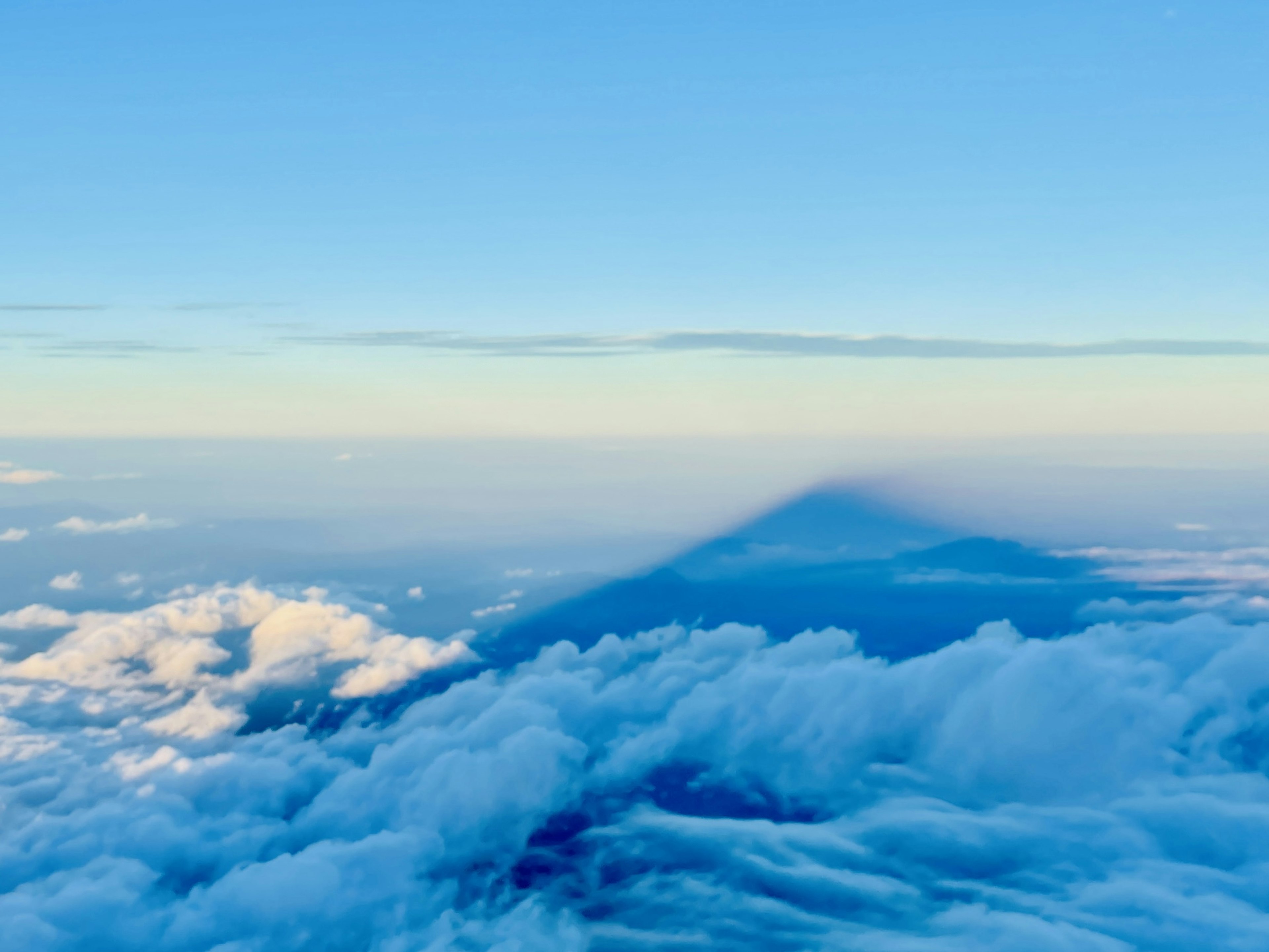 青空と雲の上に広がる影のある山の風景