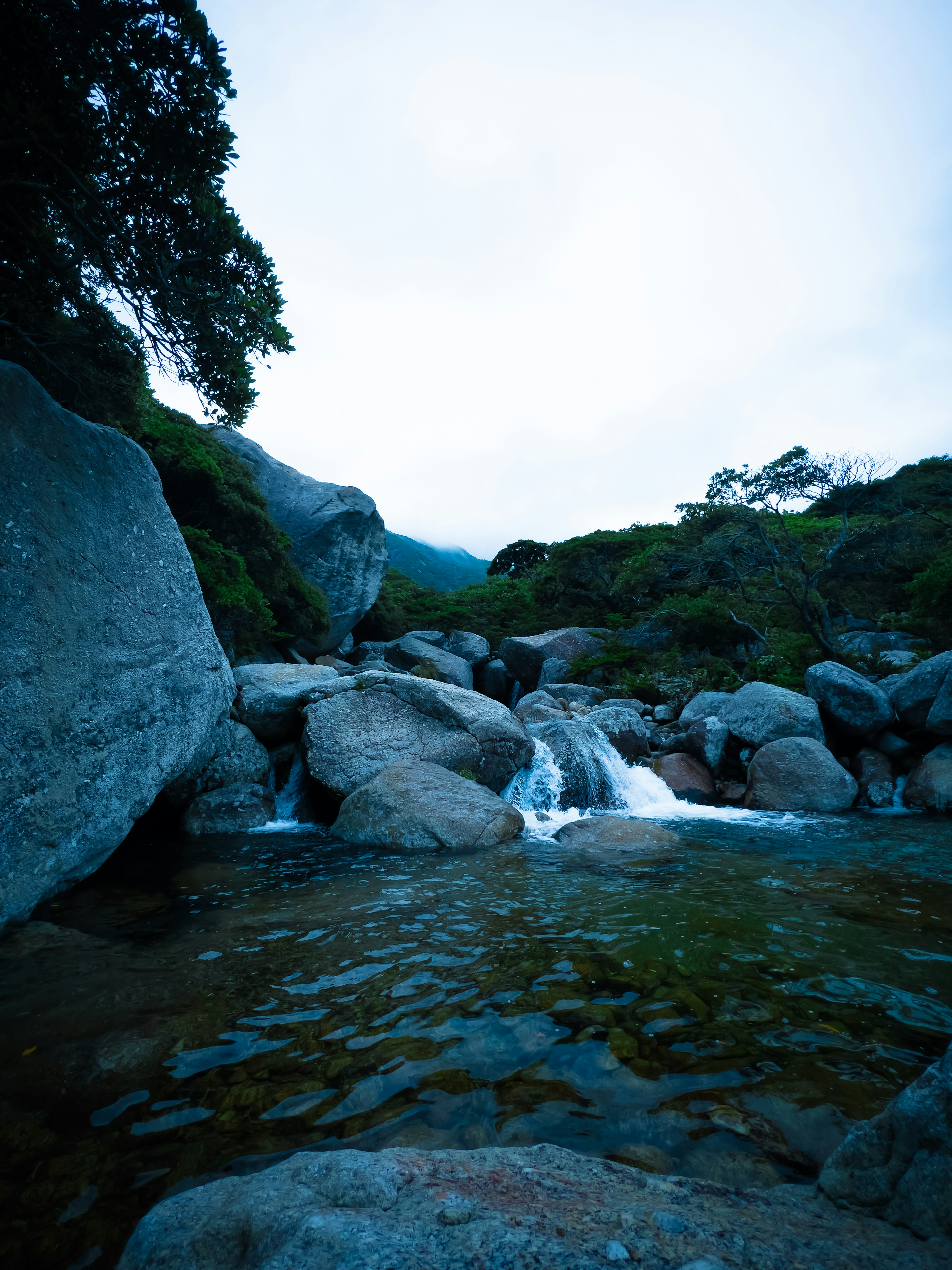 青い水と大きな岩がある静かな渓流の風景