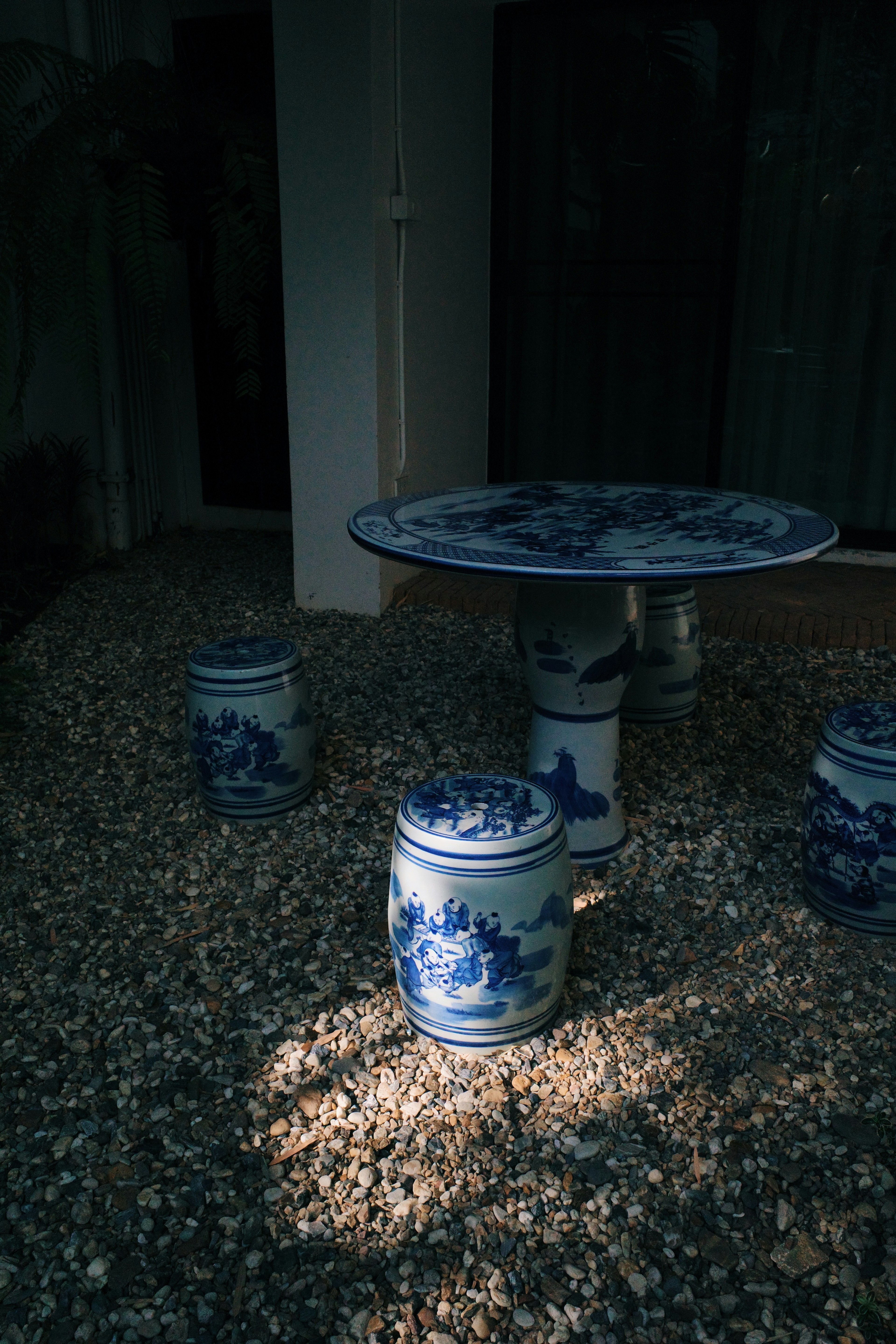 Blue ceramic table and stools arranged on gravel surface