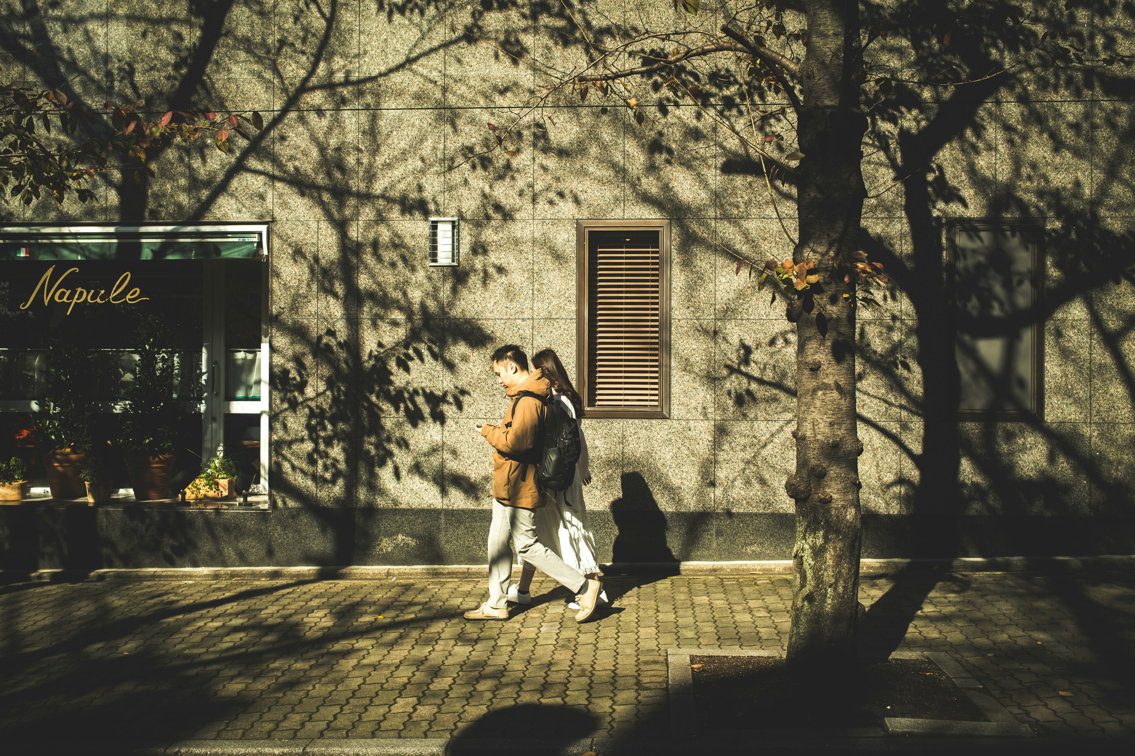 Pareja caminando por una calle de otoño con sombras de árboles