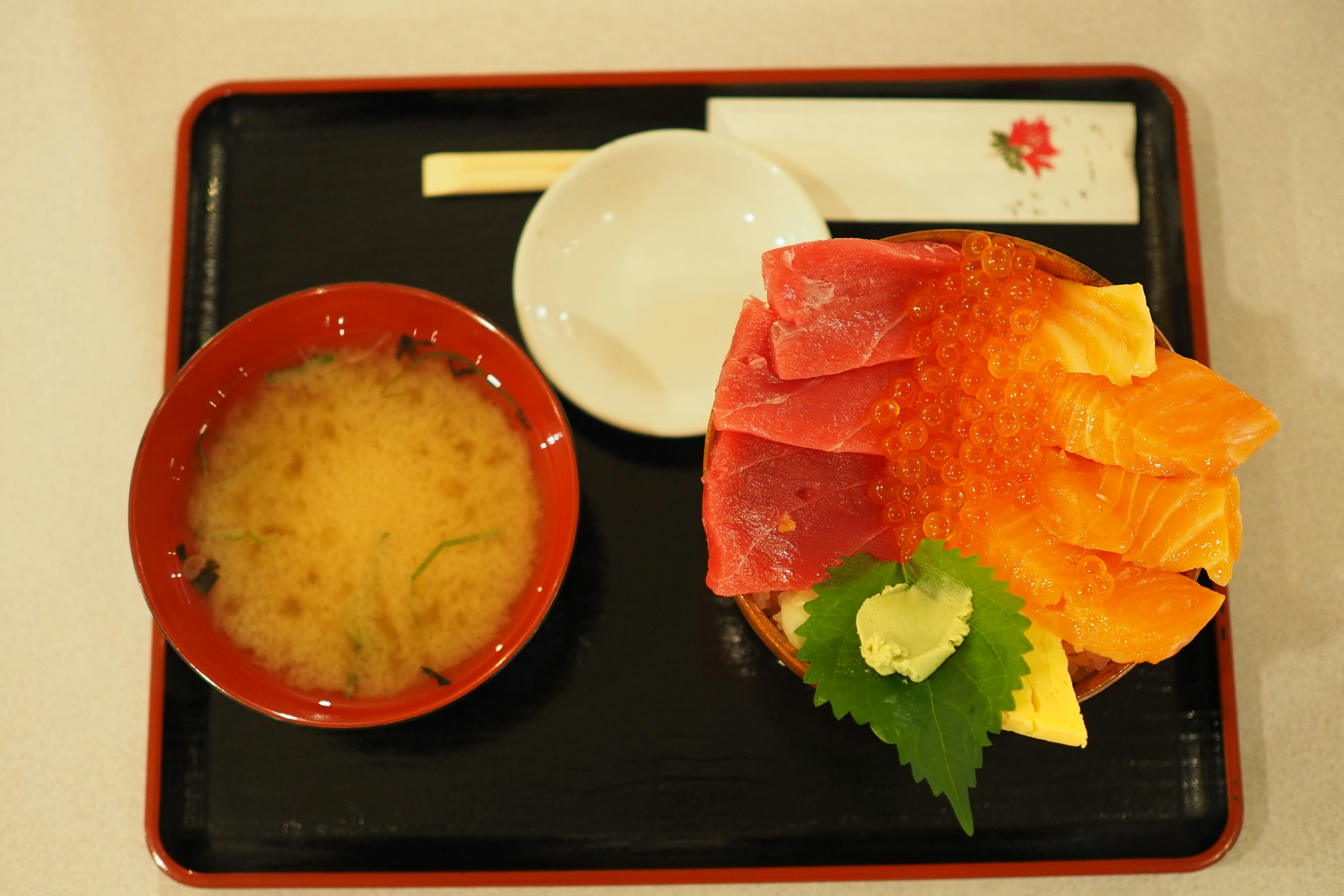 Fresh sashimi arranged on a red plate with miso soup