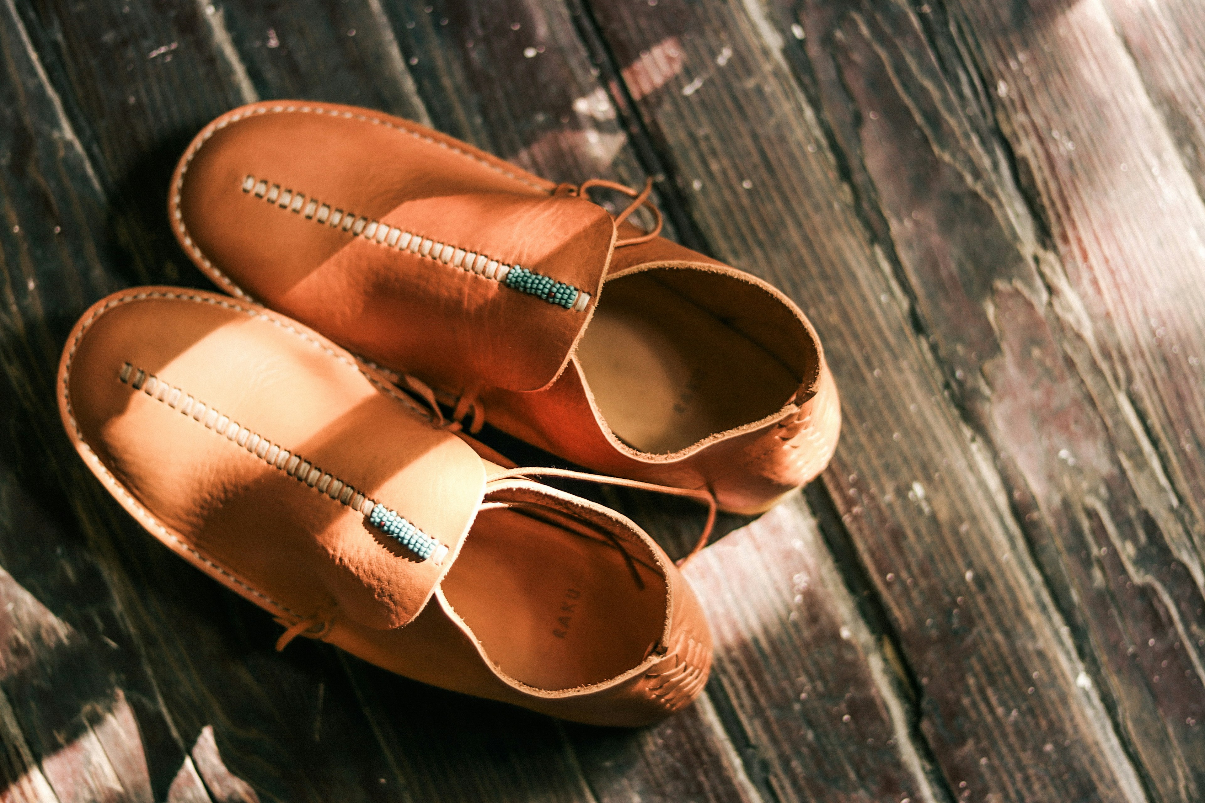 Orange leather shoes placed on wooden floor