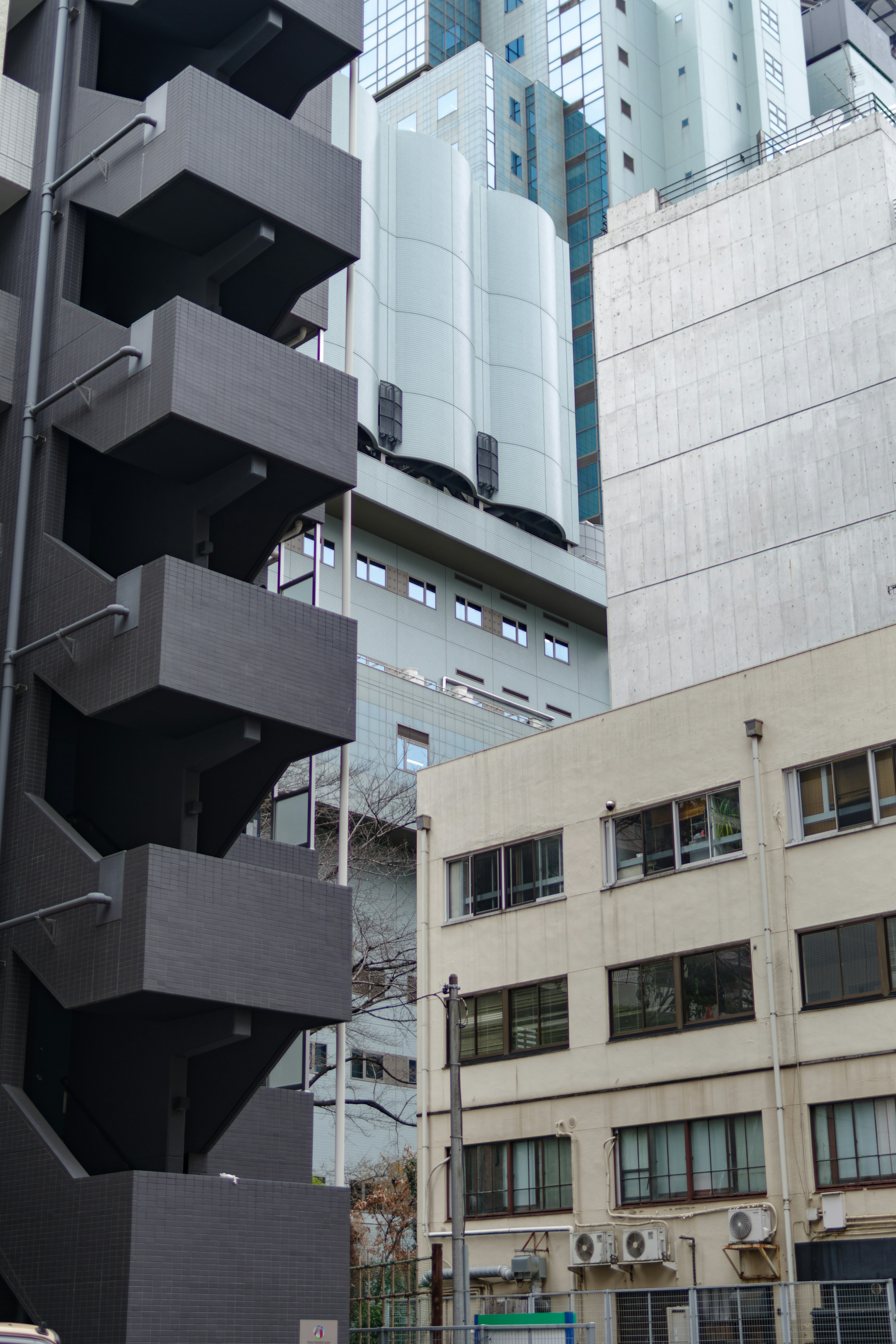 Vista de una escalera negra al lado de un edificio de concreto en un entorno urbano