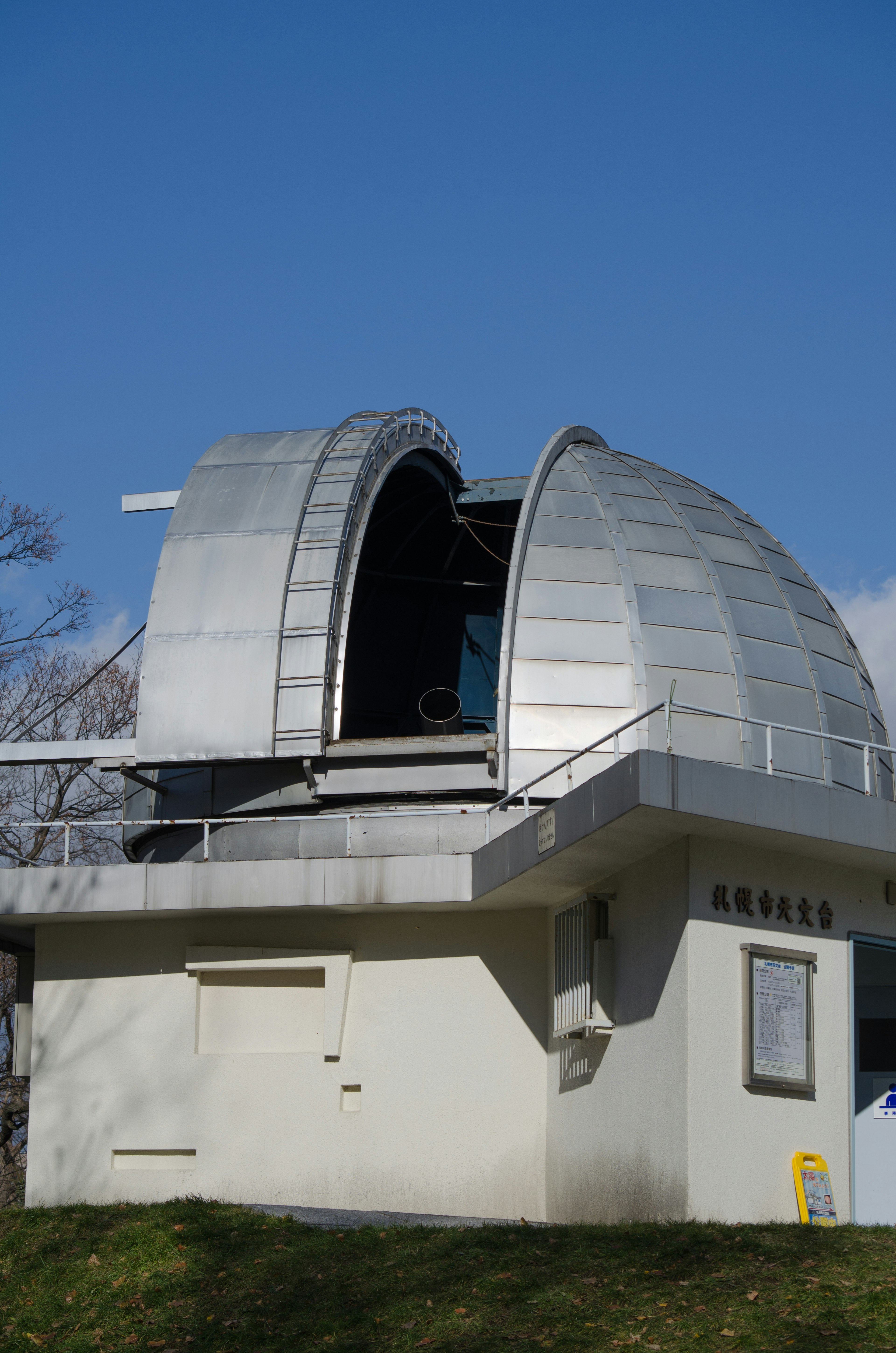 銀色のドーム型天文台が青空の下にある