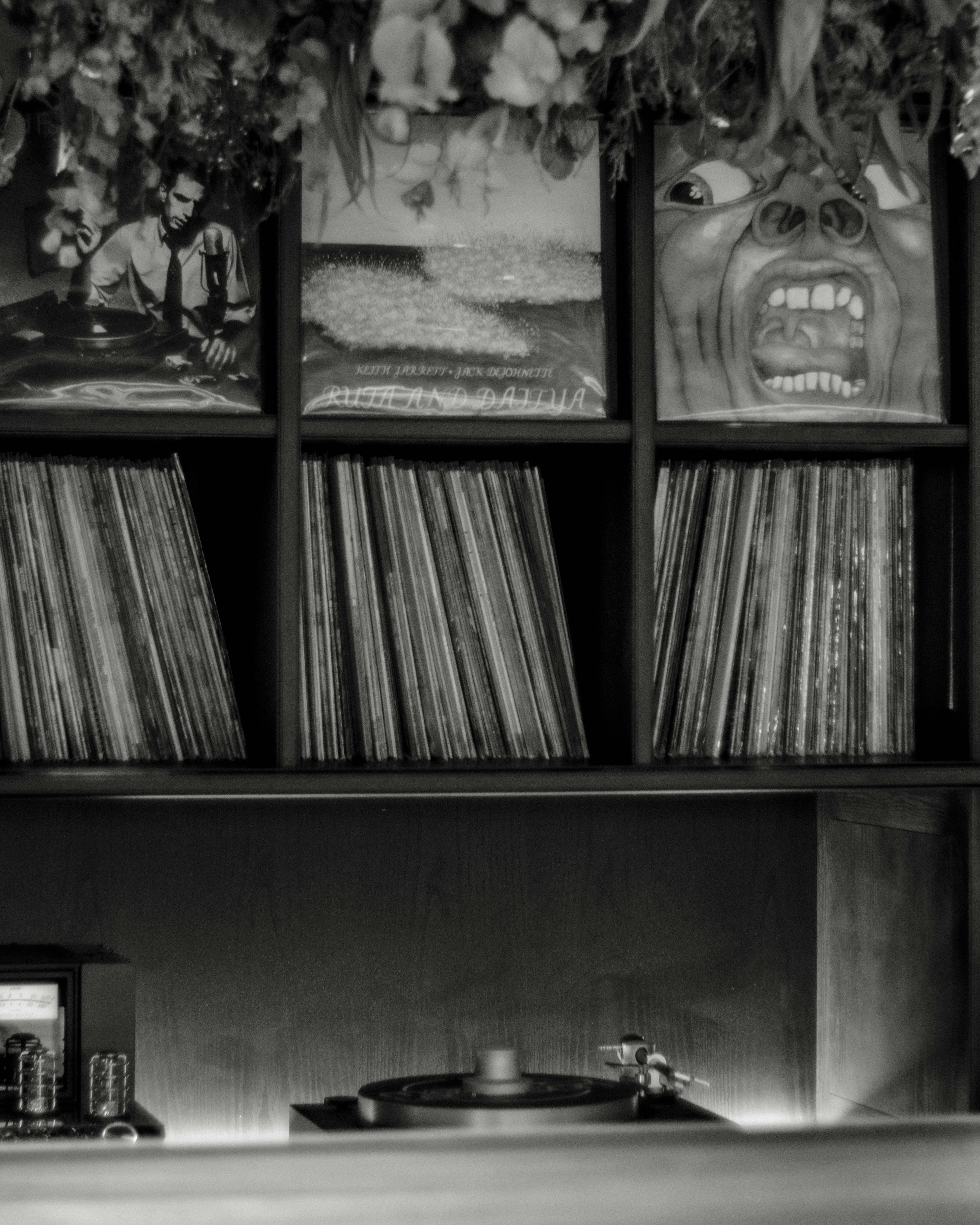 Escena interior en blanco y negro con un tocadiscos y estantes de discos de vinilo