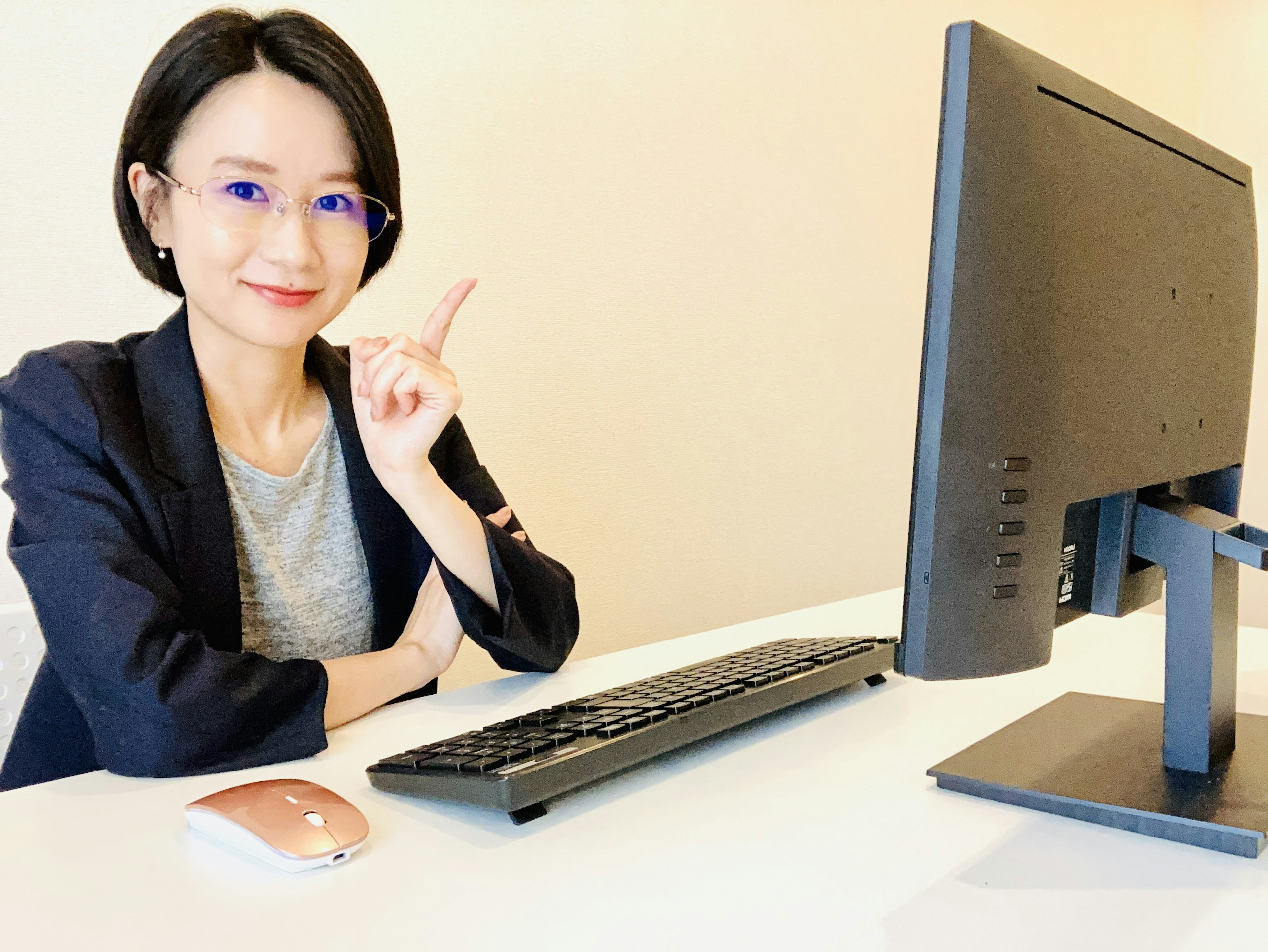 A woman sitting at a desk with a computer giving a thumbs up