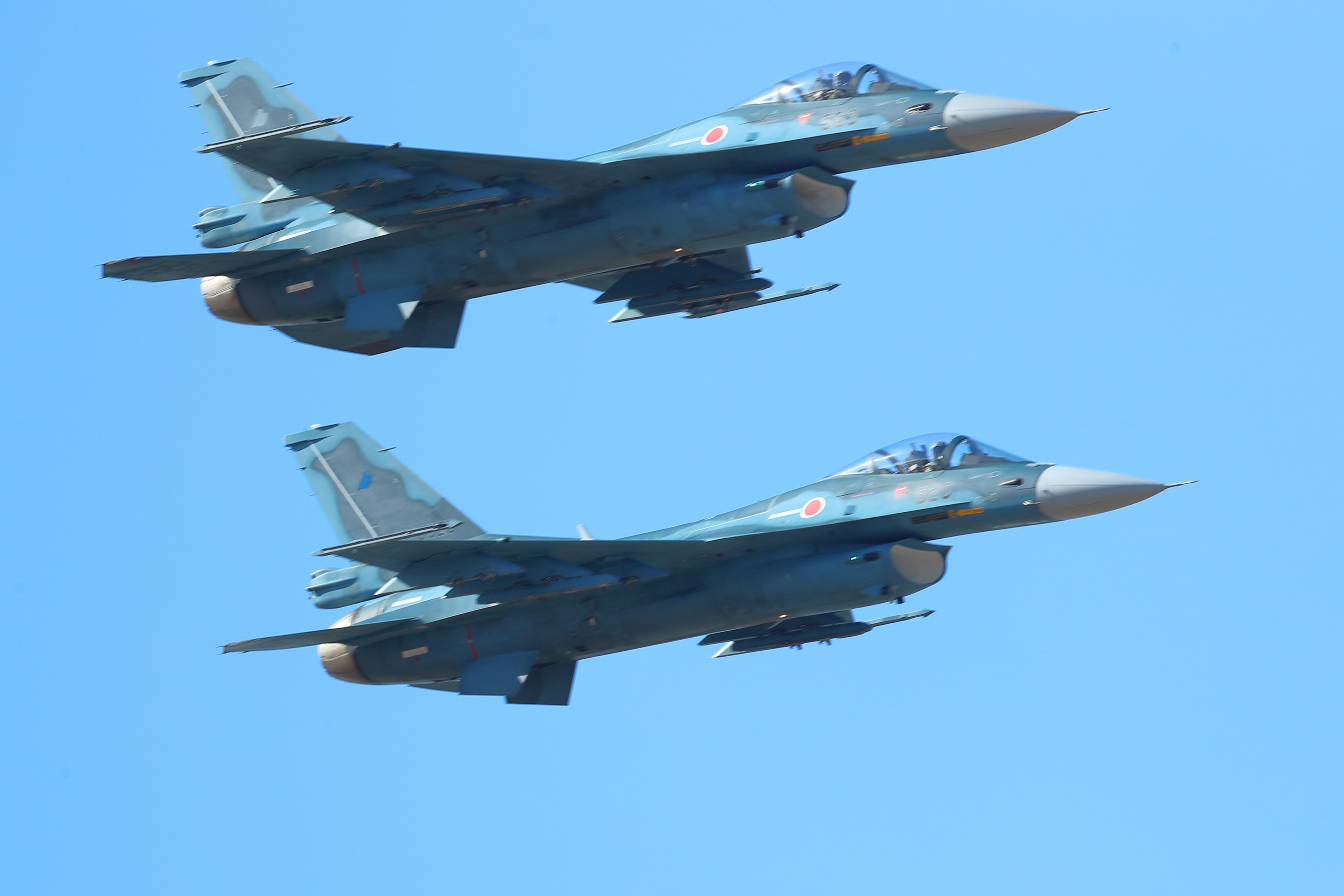 Two fighter jets flying in a blue sky